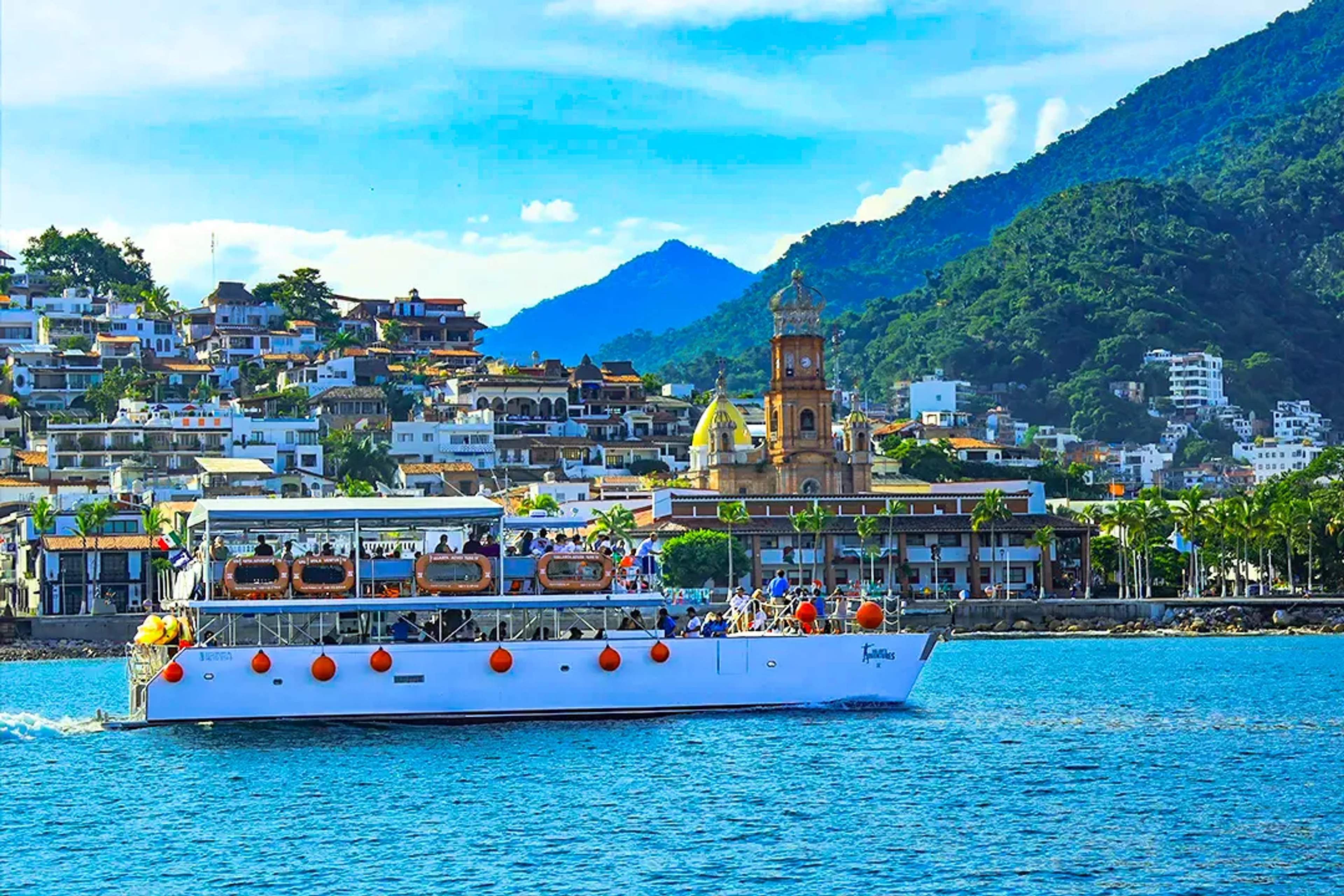 Catamarán frente a Puerto Vallarta, con la Iglesia de Guadalupe y las montañas de la Sierra Madre al fondo.