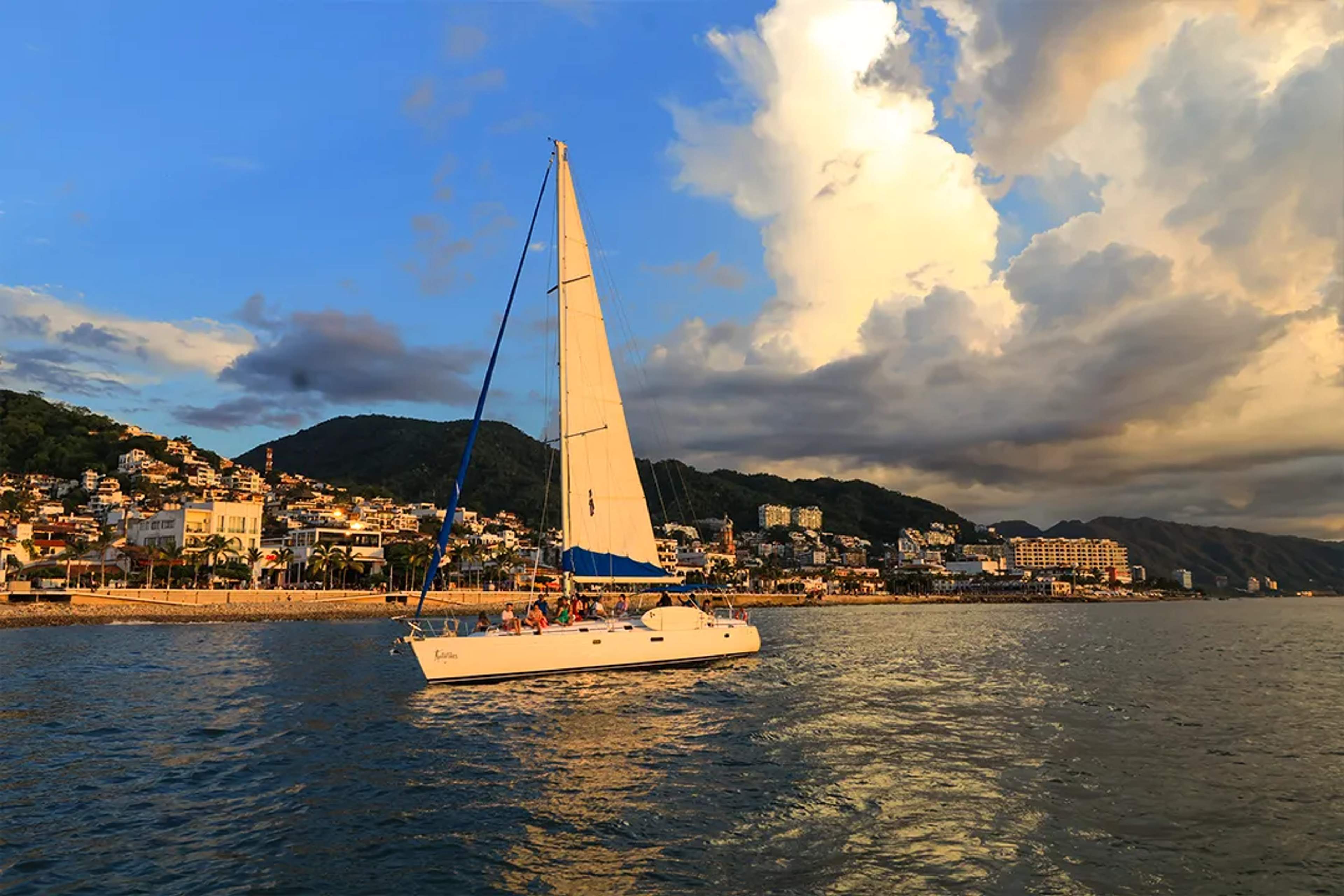 Tour de vela de lujo en Puerto Vallarta al atardecer, catamarán navegando con vistas a la costa