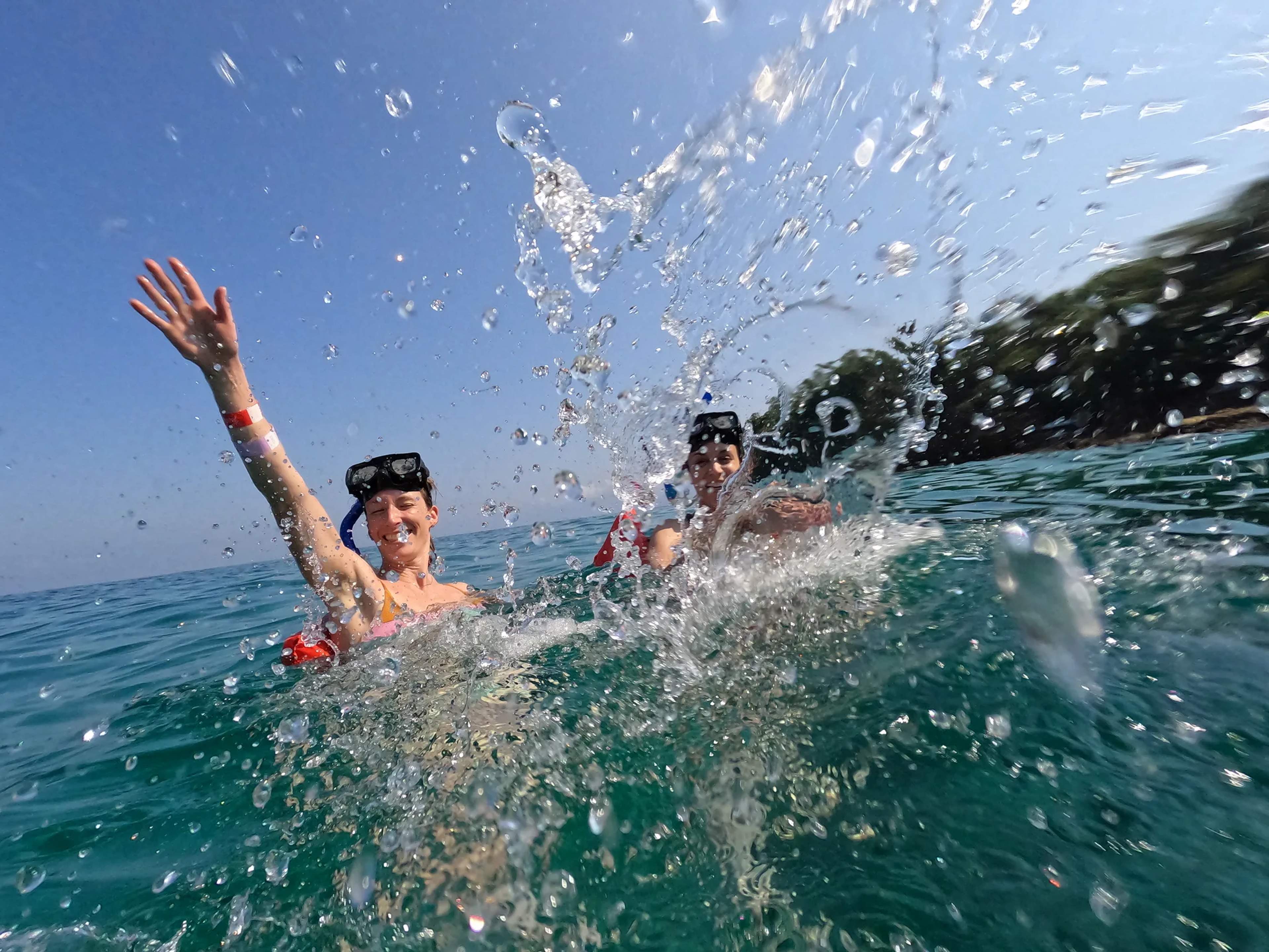 Tourists snorkel and splash in the clear turquoise waters of a Mexican coastal cove during a beach excursion.