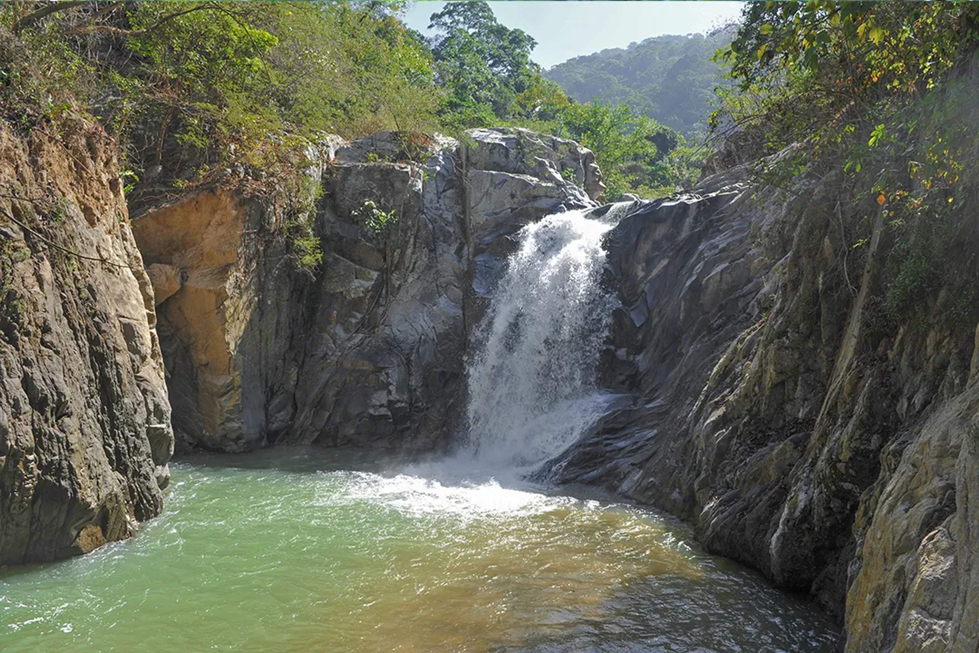 Hidden waterfall canyon near Puerto Vallarta with natural pool, rock formations, and lush jungle surroundings