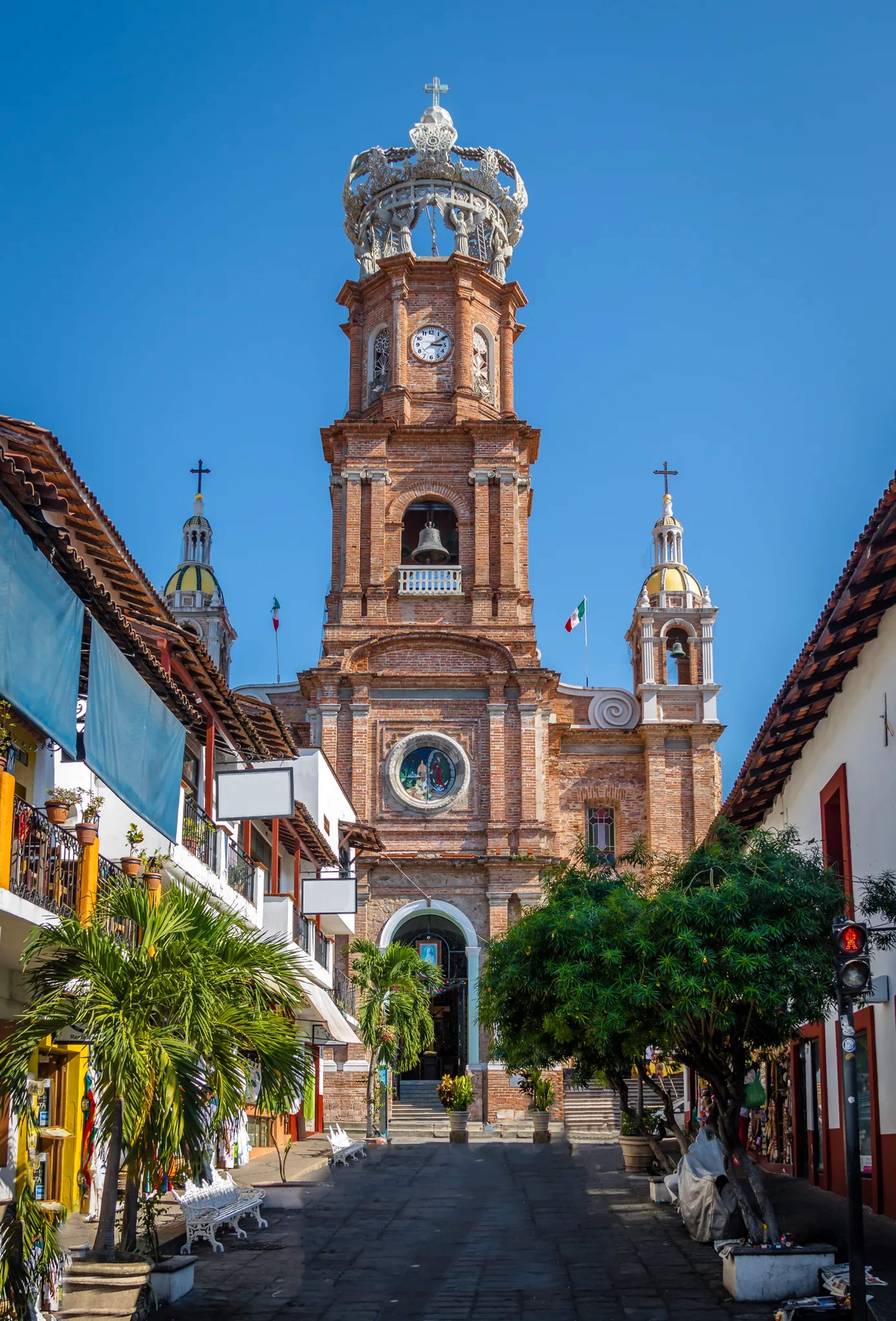 Catedral colonial con torre de ladrillo y cúpula corona que domina la plaza principal de Puerto Vallarta.