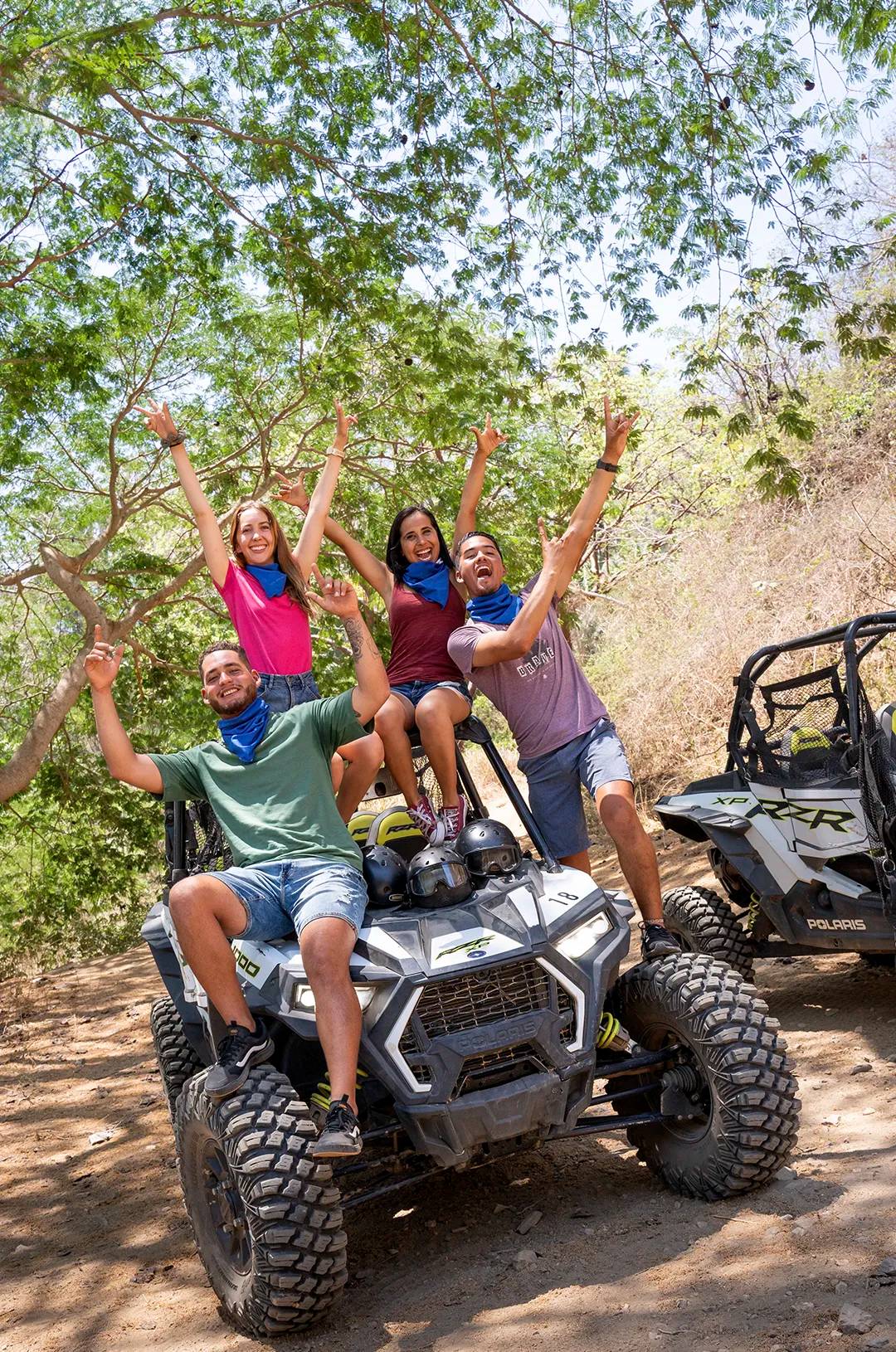 Joyful group on a Polaris RZR ATV posing for a photo amidst a tropical jungle near Sayulita.