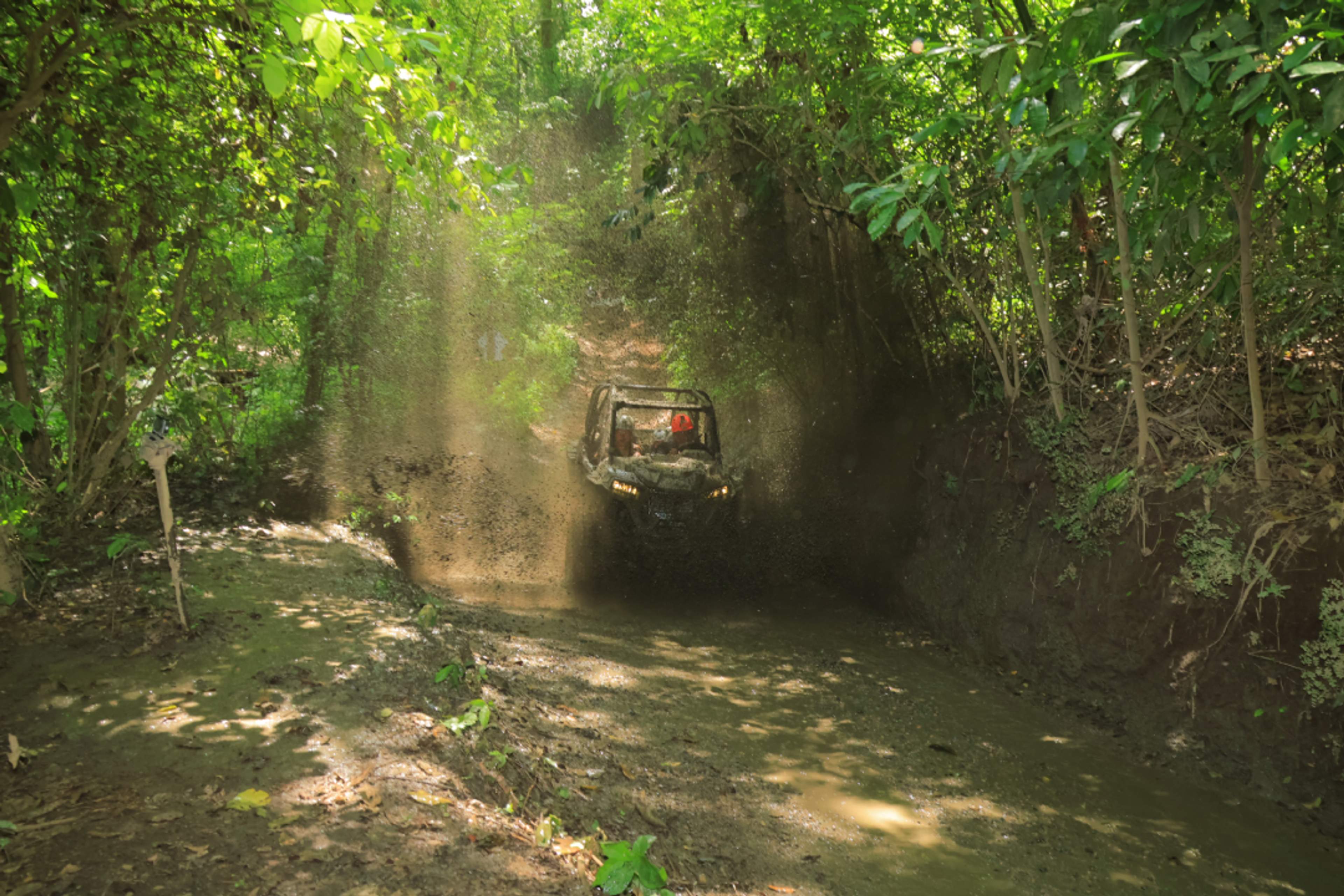 Turistas conduciendo vehículos todoterreno Polaris® RZR por un sendero rocoso en la jungla durante un tour de aventura en Puerto Vallarta.