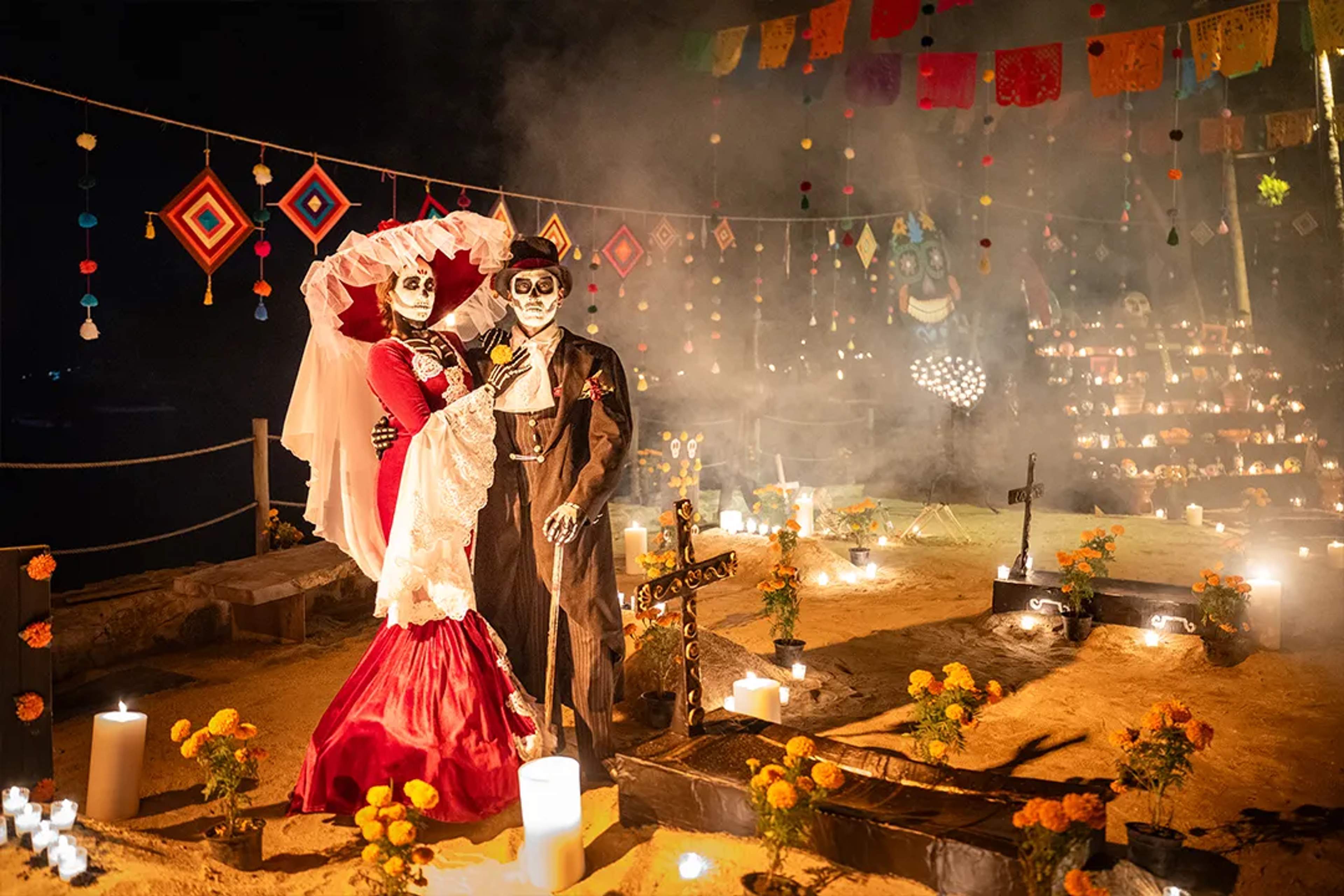 Day of the Dead celebration with Catrina couple, candles, marigolds and traditional altar at night.