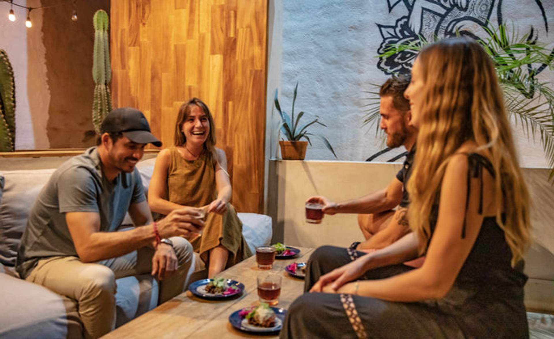  Un grupo de amigos disfruta de tacos y bebidas juntos en un acogedor y bien decorado espacio interior.