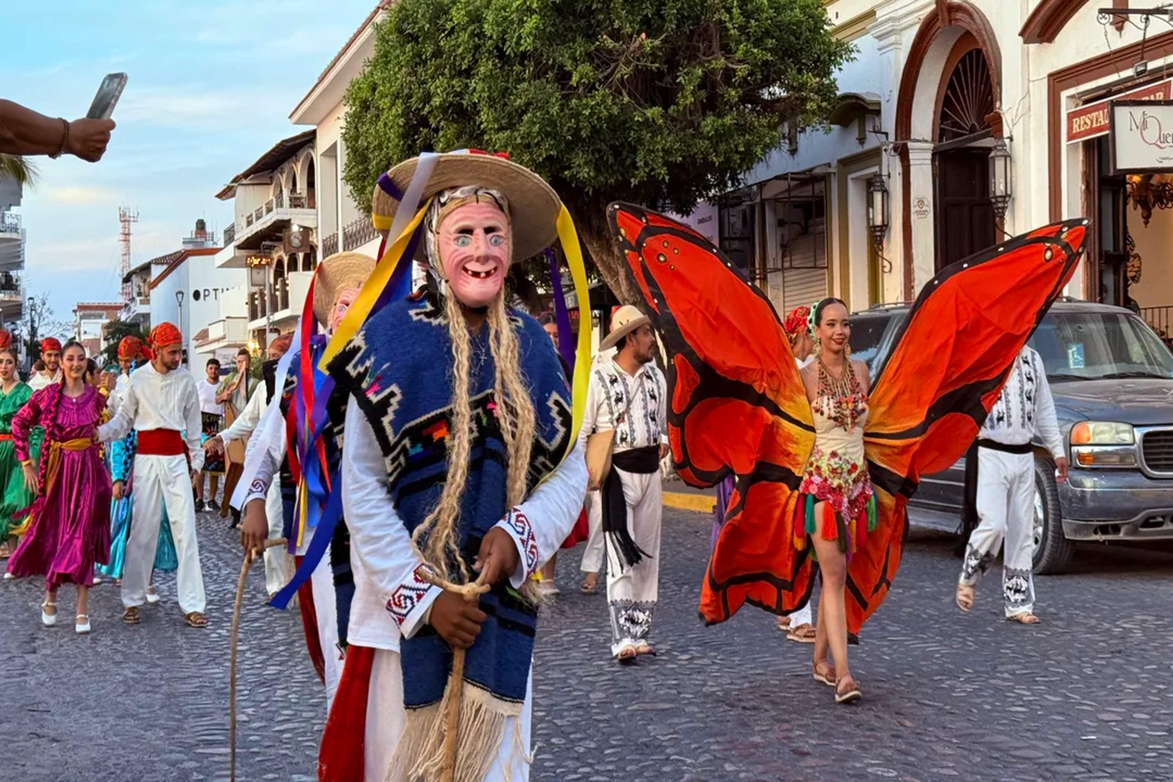 Traditional parade with masks, butterfly wings, and folkloric costumes in Puerto Vallarta.