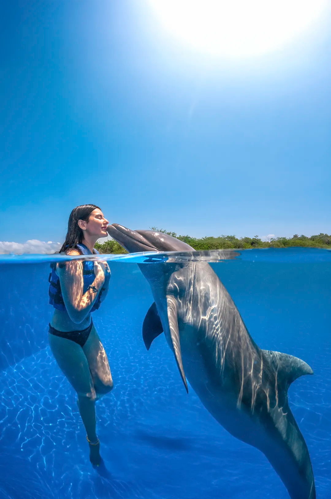 Mujer compartiendo momentos emotivos en el agua con delfines en Puerto Vallarta.