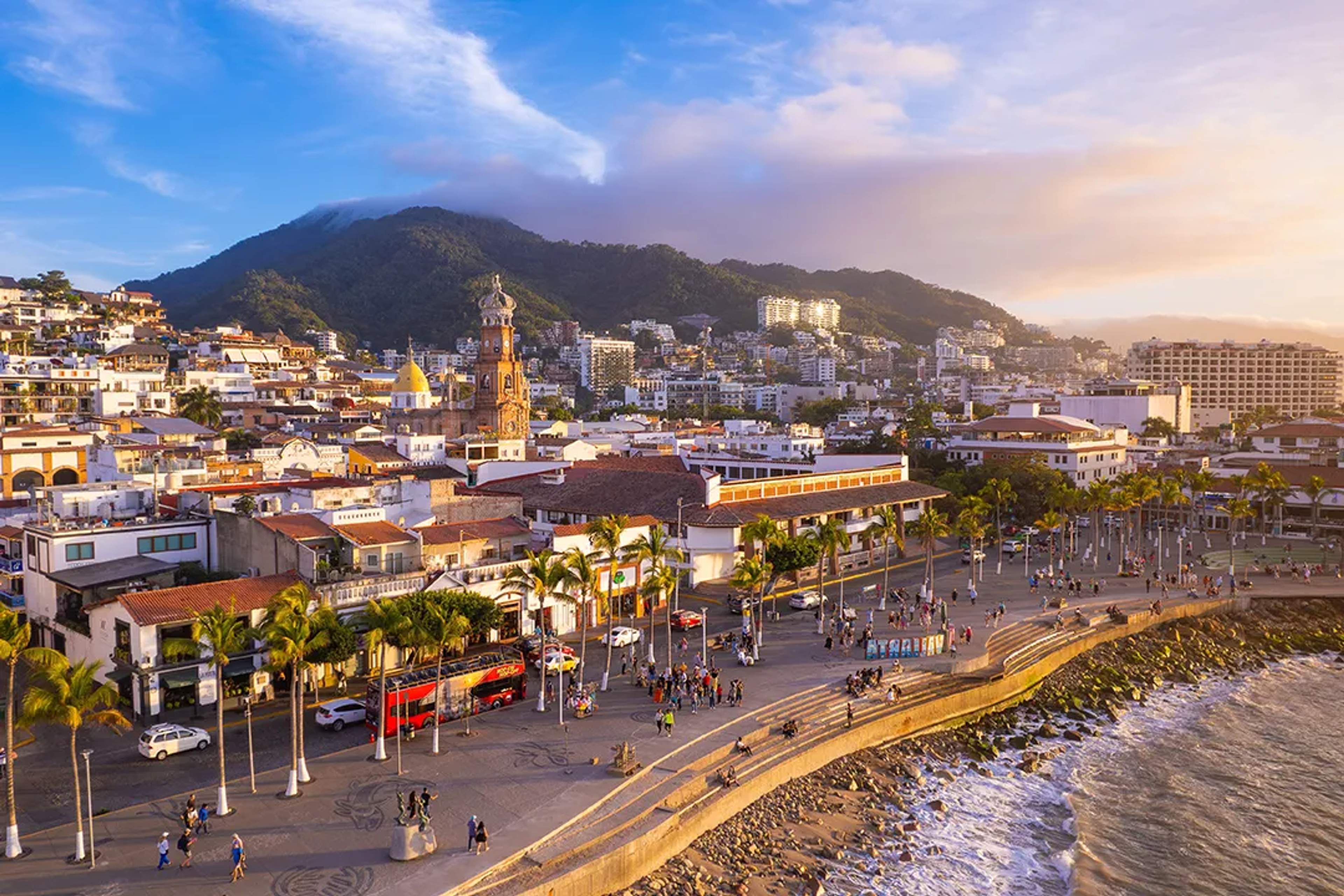Malecón de Puerto Vallarta al atardecer con vista al mar, centro histórico y montañas de la Sierra Madre