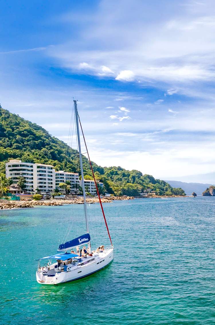 Sailboat sailing by the south shore of Puerto Vallarta on a bright day.