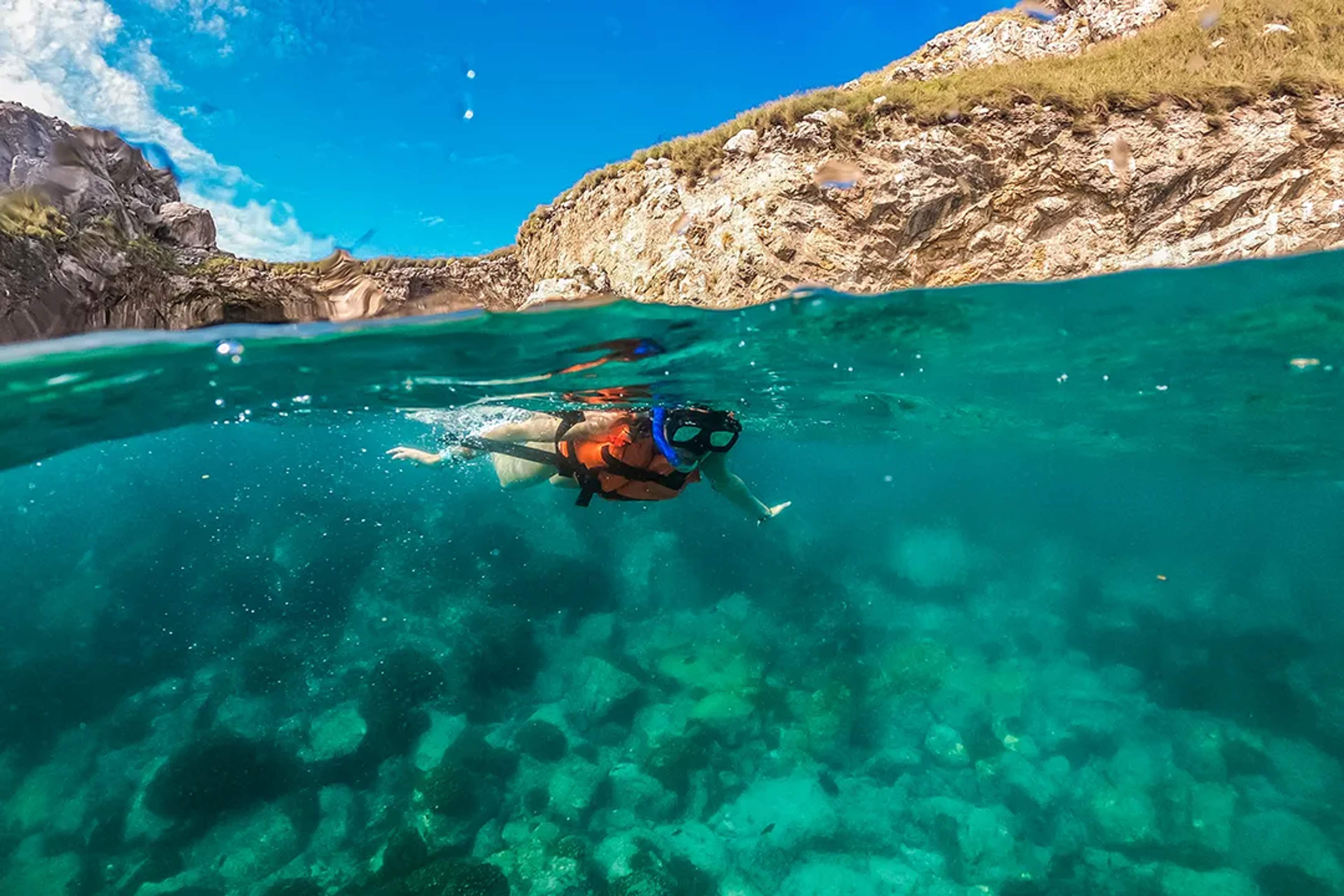 Persona practicando snorkel en las aguas turquesa de las Marietas sobre arrecifes rocosos