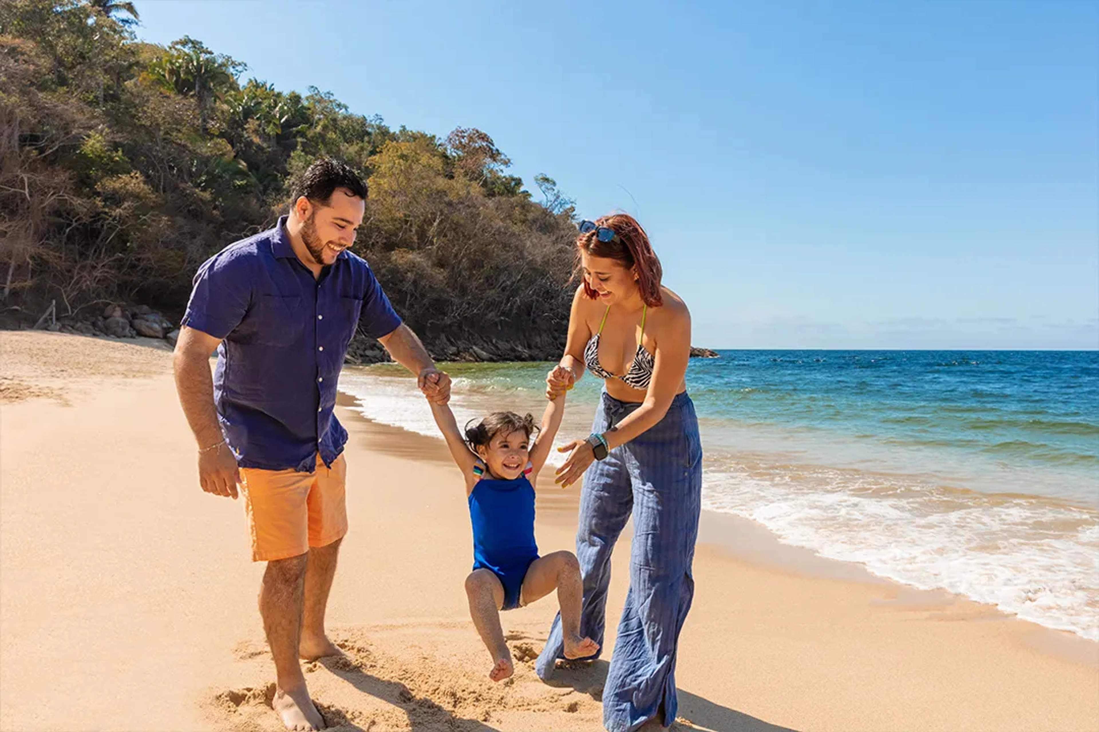 Family enjoying a sunny beach day in Majahuitas, Puerto Vallarta, with golden sand and crystal-clear waters