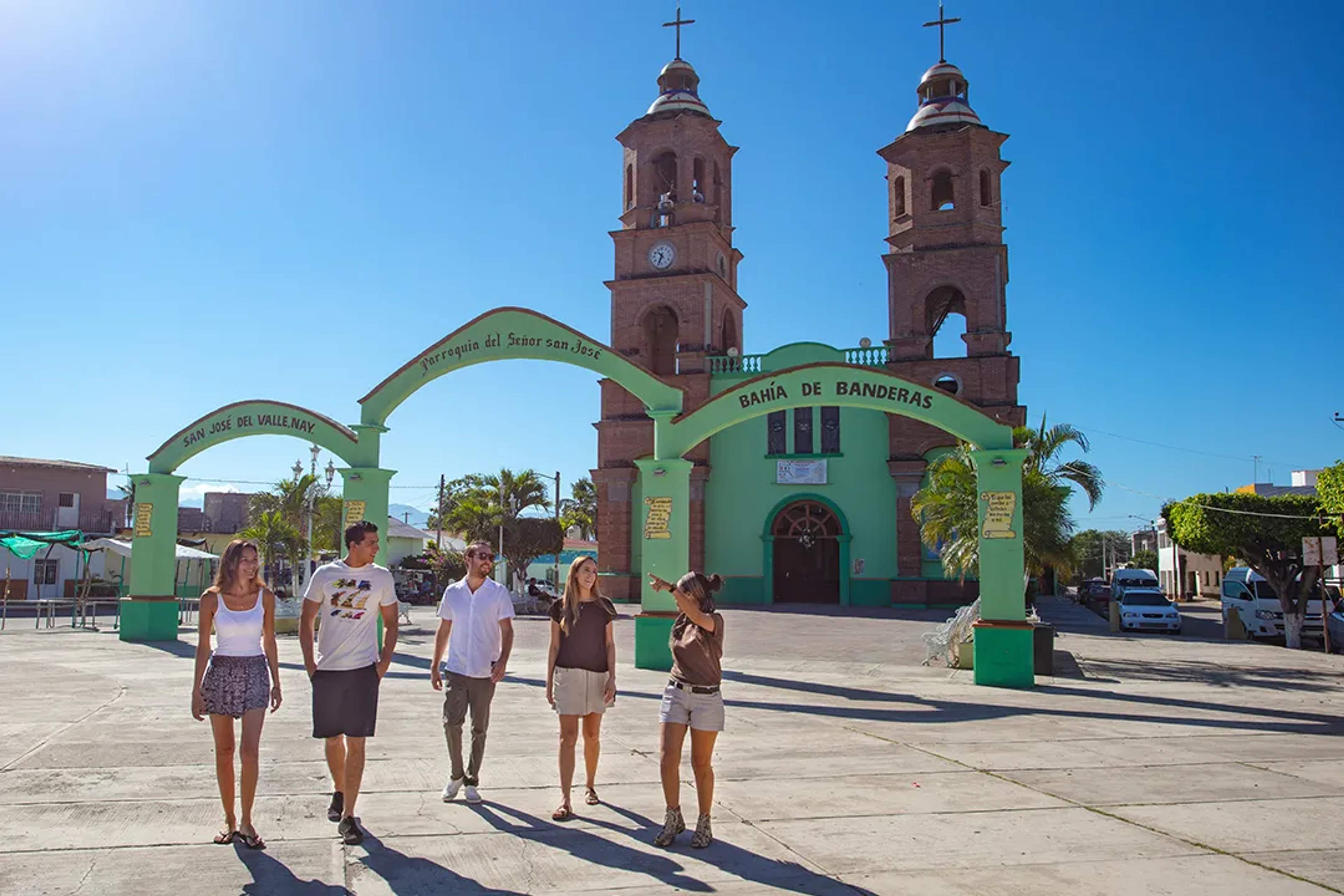 Visitors walking at San José del Valle main square, church archway and twin towers in Bahía de Banderas