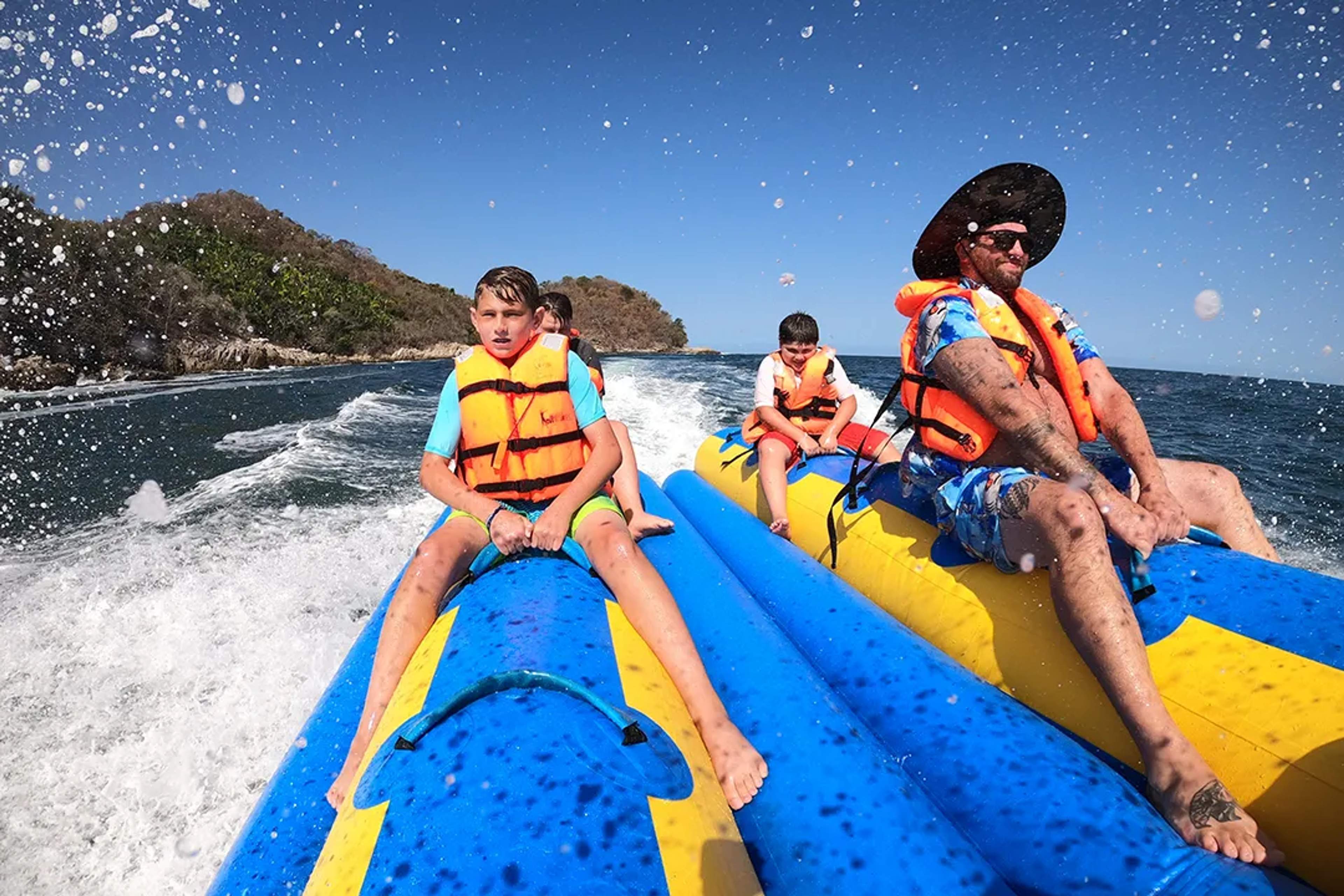 Familia en paseo en banana inflable en Las Caletas, Puerto Vallarta disfrutando una aventura acuática, con Vallarta Adventures
