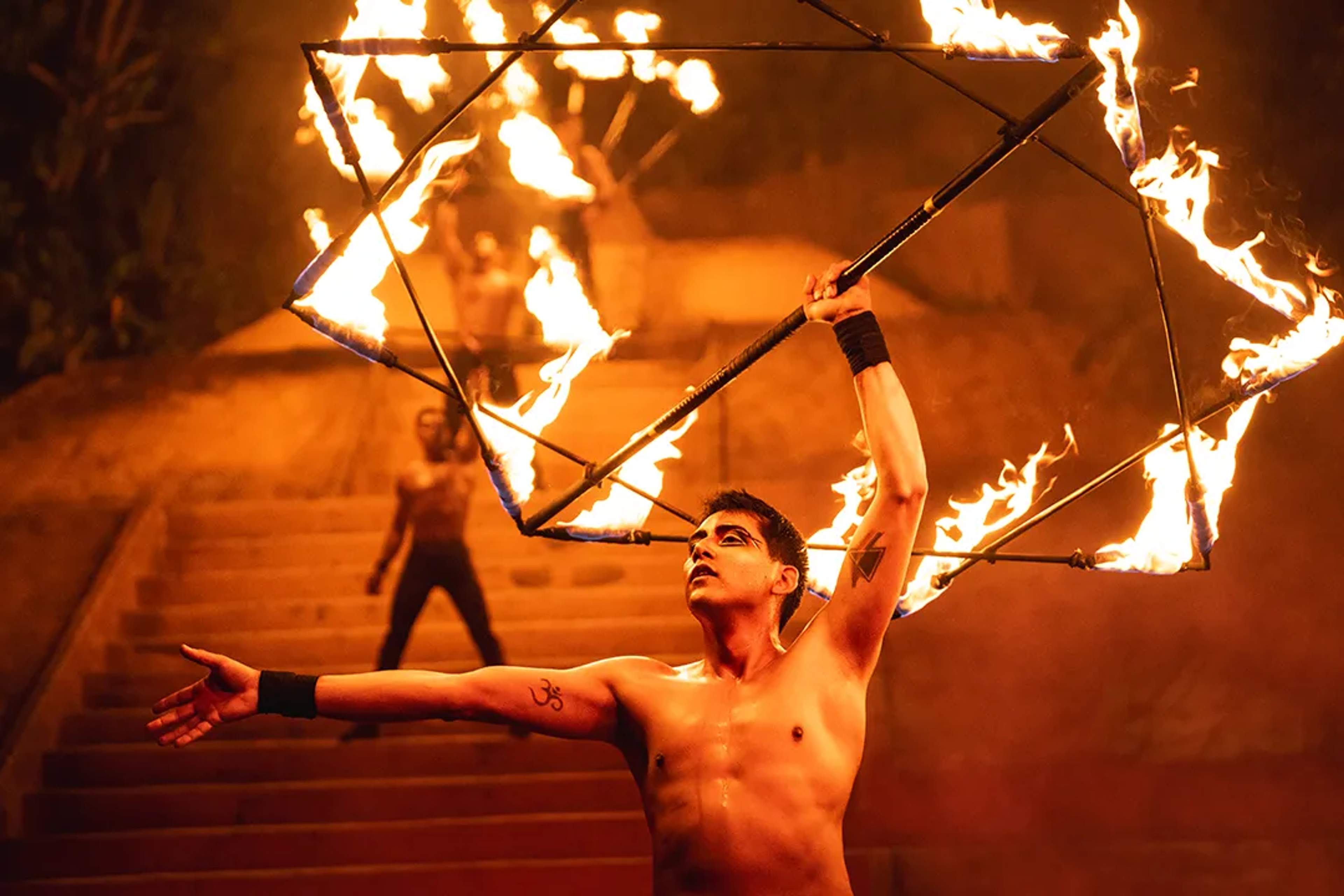 Fire performer at ALMA show in Puerto Vallarta holding flaming prop during nighttime ritual act