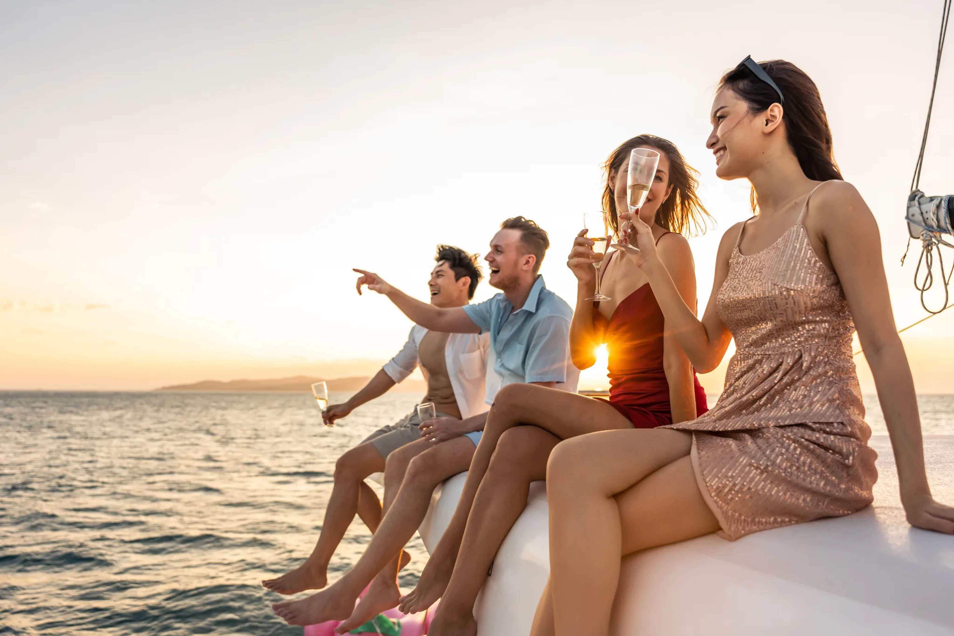 Tourists enjoy drinks and conversation aboard a sailboat during a golden Pacific sunset off the Puerto Vallarta coast.