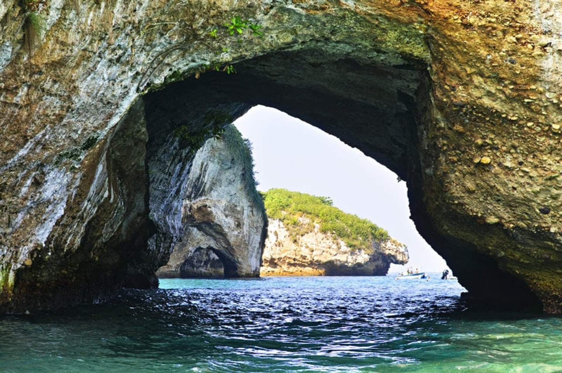 Vista a través de las formaciones de arcos de Los Arcos en Puerto Vallarta, mostrando las islas rocosas y el agua azul clara.
