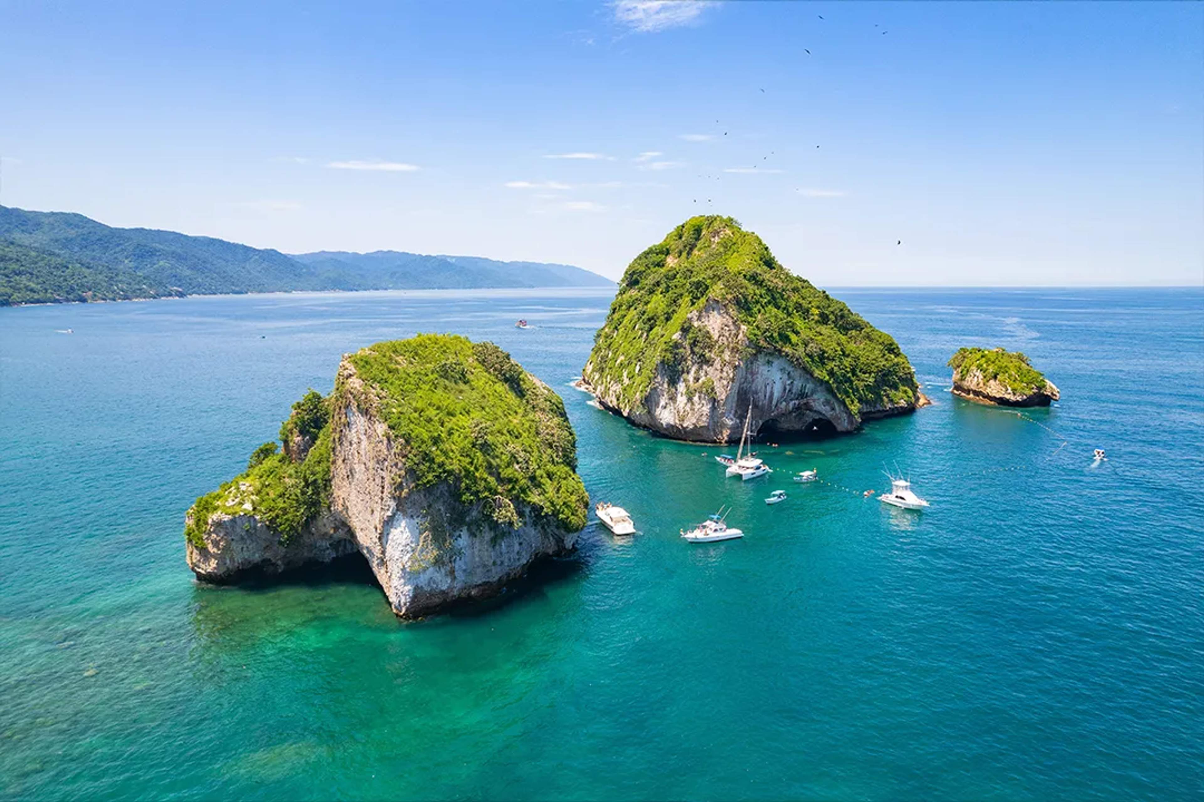 Aerial view of Los Arcos Marine Park in Puerto Vallarta with boats and turquoise ocean water.