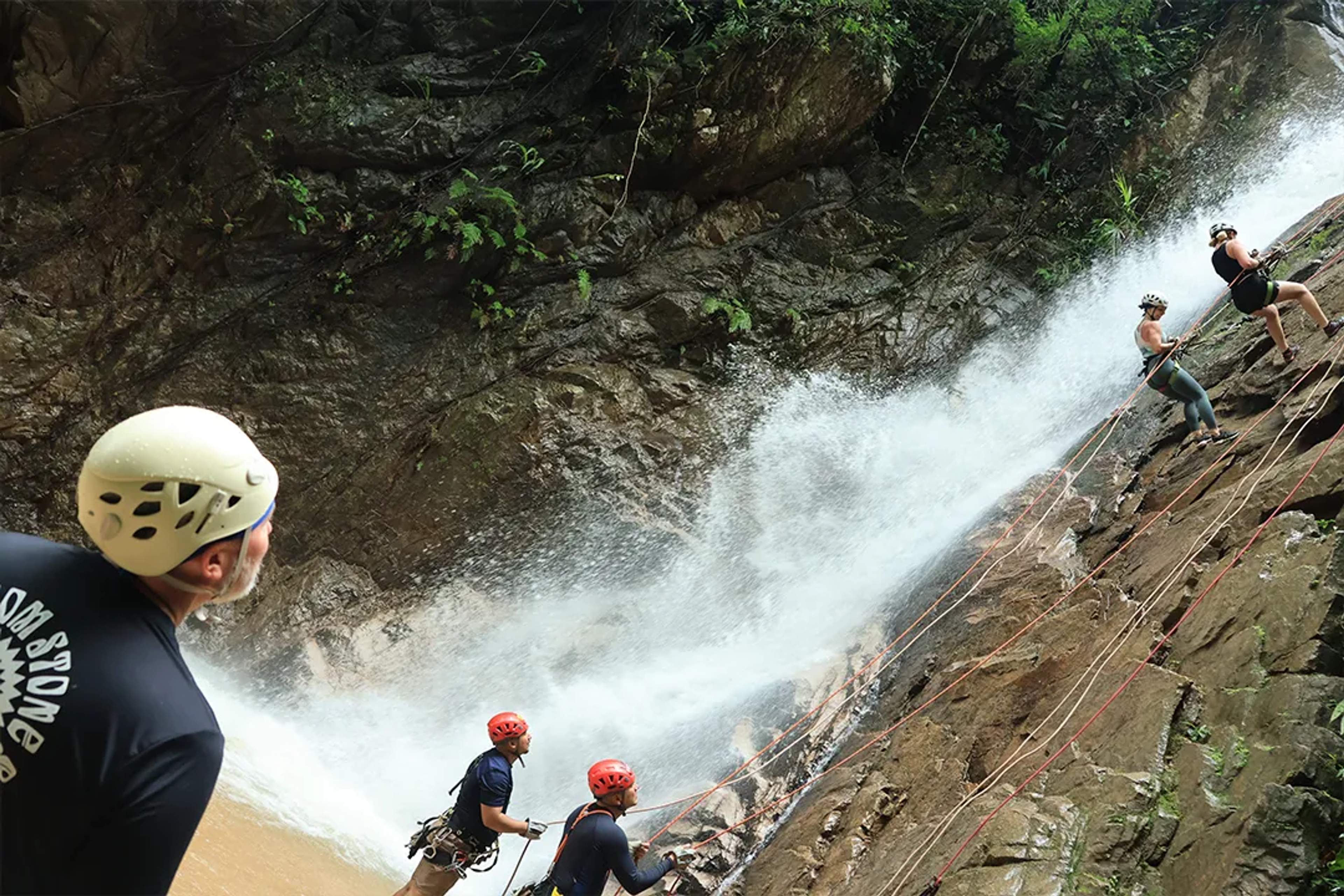 Aventura de rappel en cascada en Puerto Vallarta — aventureros descendiendo acantilados selváticos con agua corriente.
