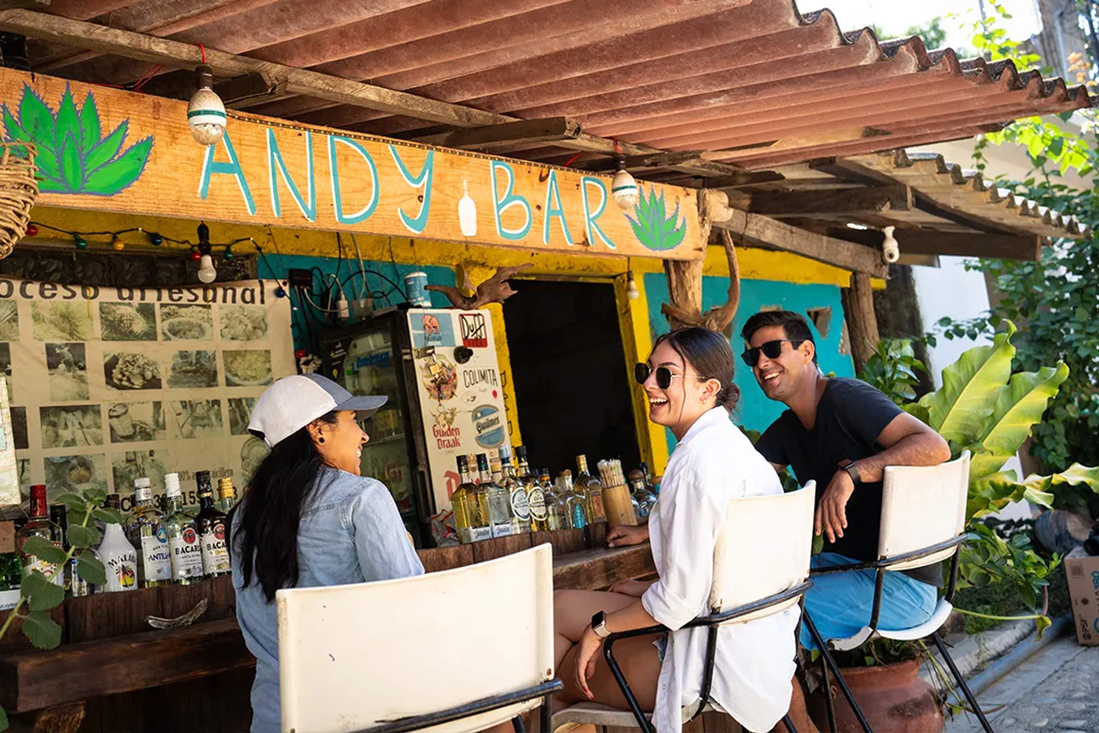 Amigos comparten risas y tragos en Andy Bar, un lugar rústico y colorido con encanto local.