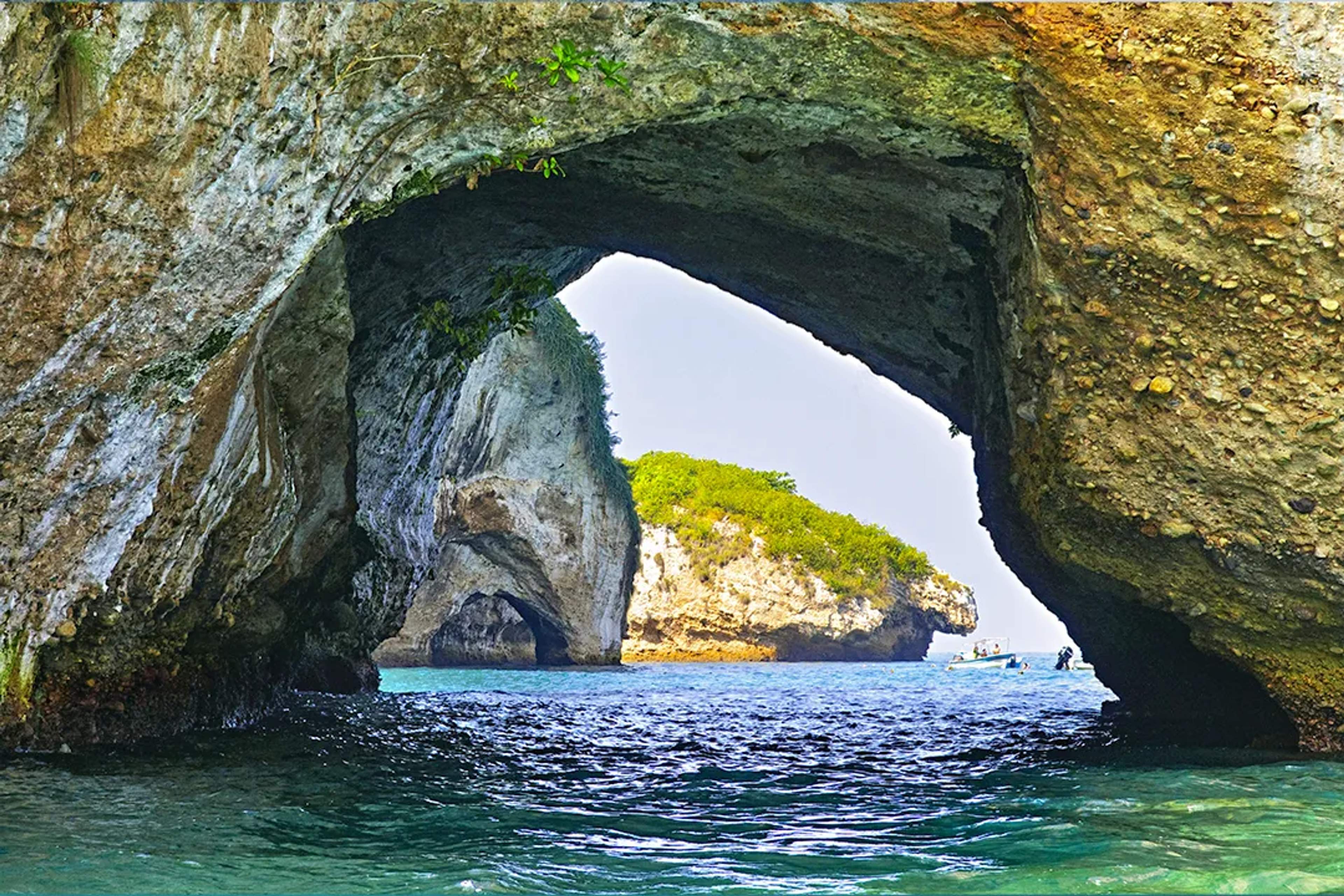 A view through the arch formations of Los Arcos in Puerto Vallarta, showcasing the rocky islands and clear blue water.