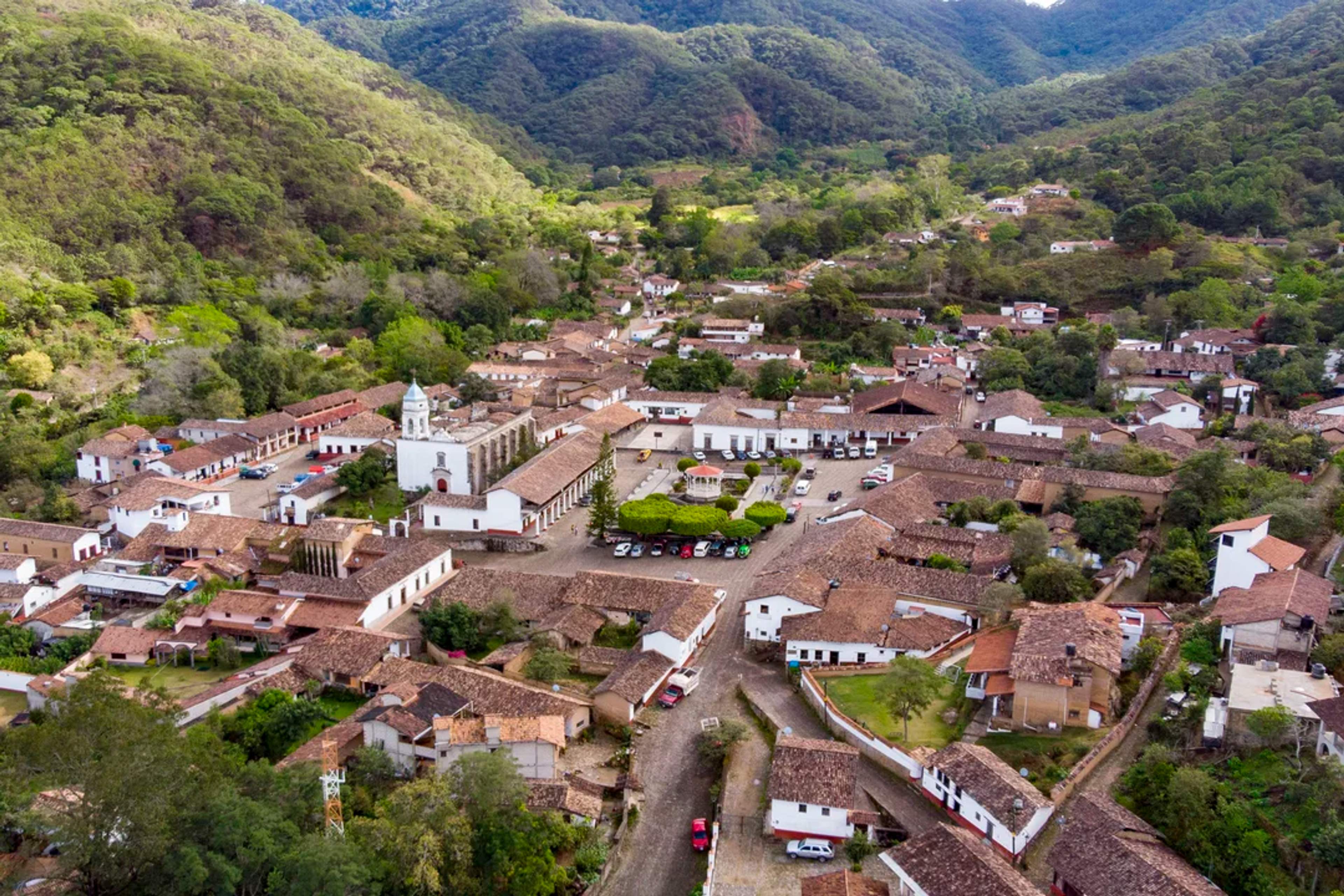Charming mountain town with colonial houses and a church surrounded by lush green hills.