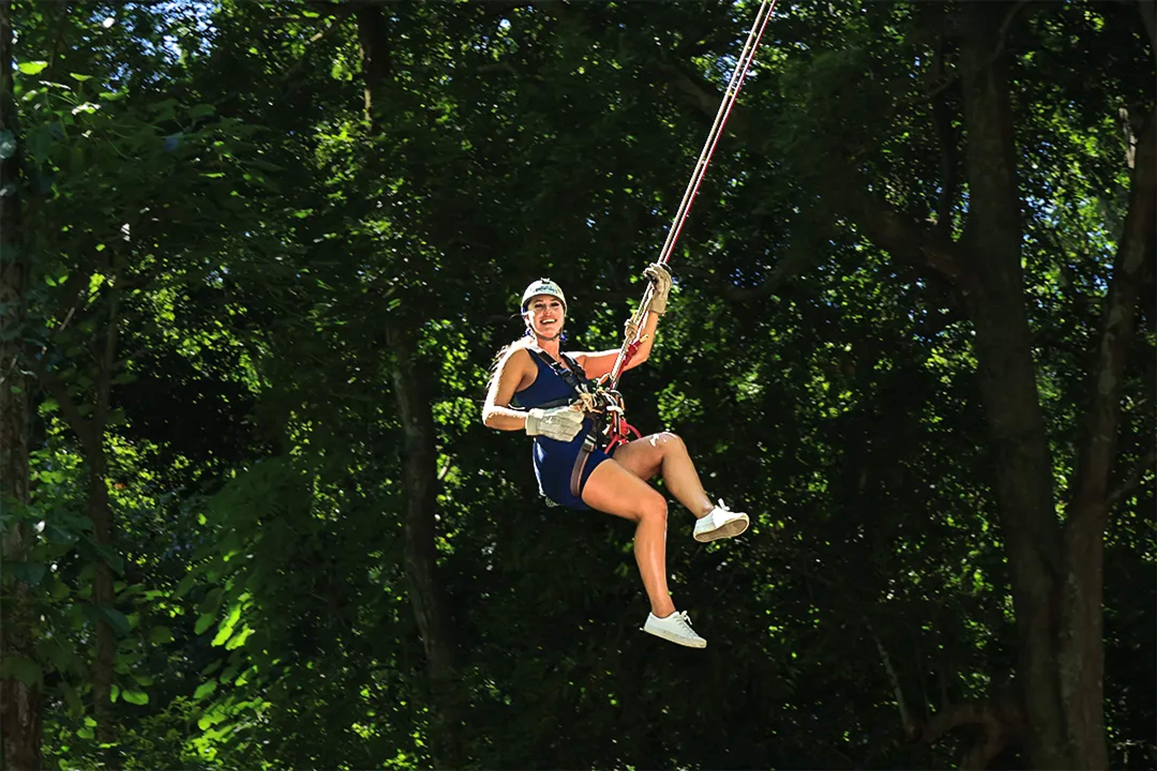 Aventurera sonriente salta del Pendulo sobre la selva, disfrutando la emoción y la libertad, en Extreme Adventure.