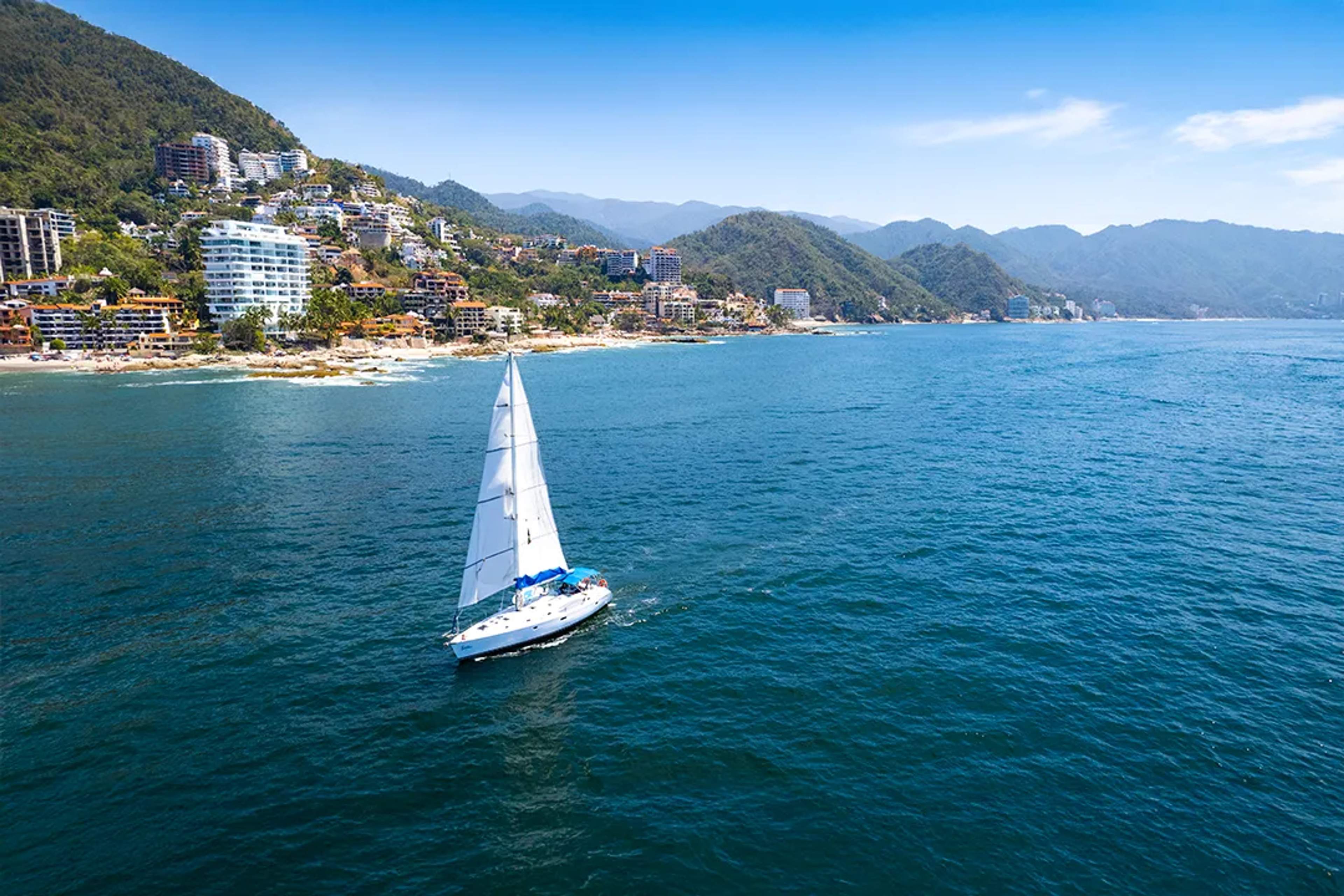 Luxury sailing tour in Puerto Vallarta with scenic coastline views and Sierra Madre mountains backdrop