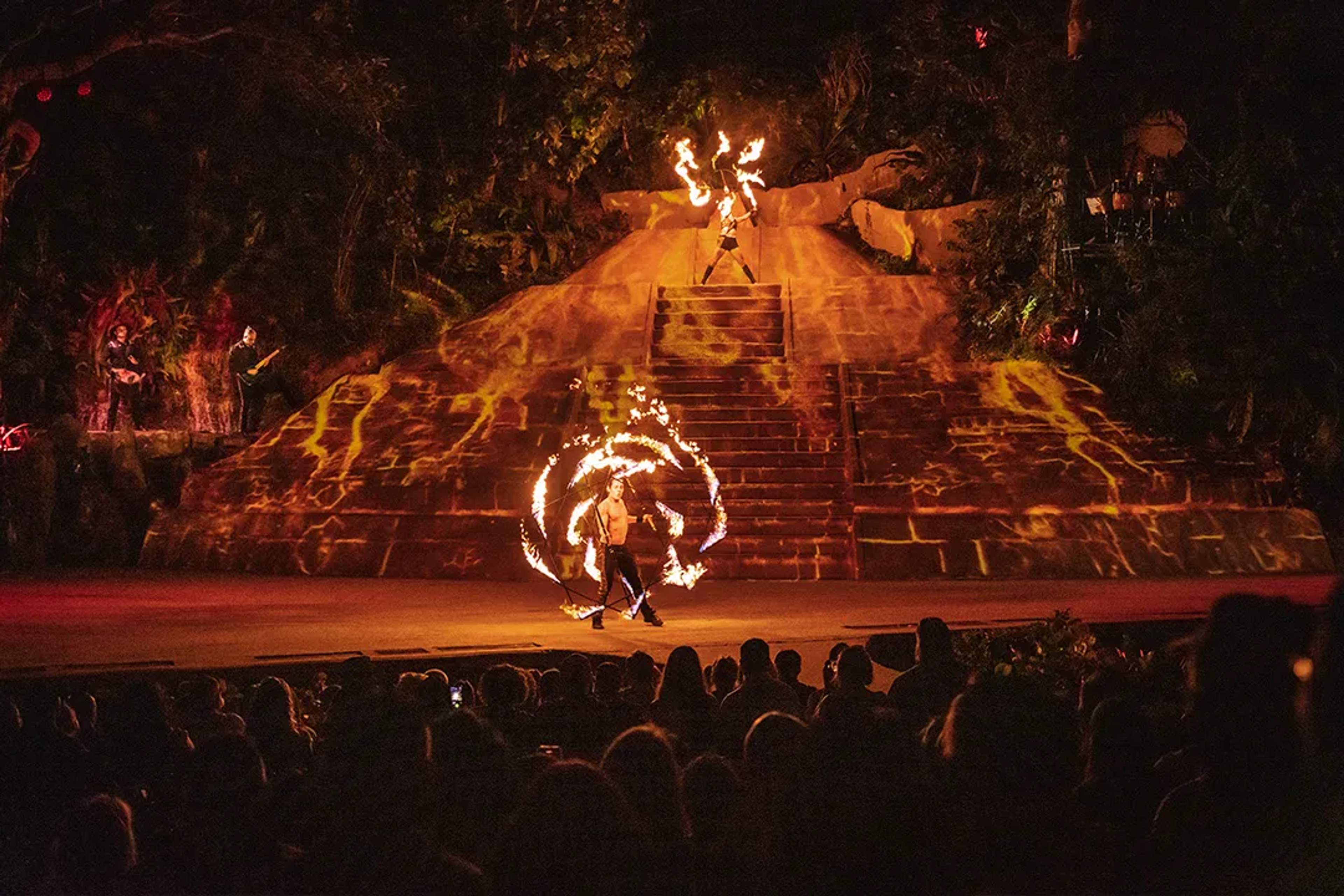 Fire dancers perform before a pyramid backdrop, mesmerizing the crowd with swirling flames, at Rhythms of the Night show.