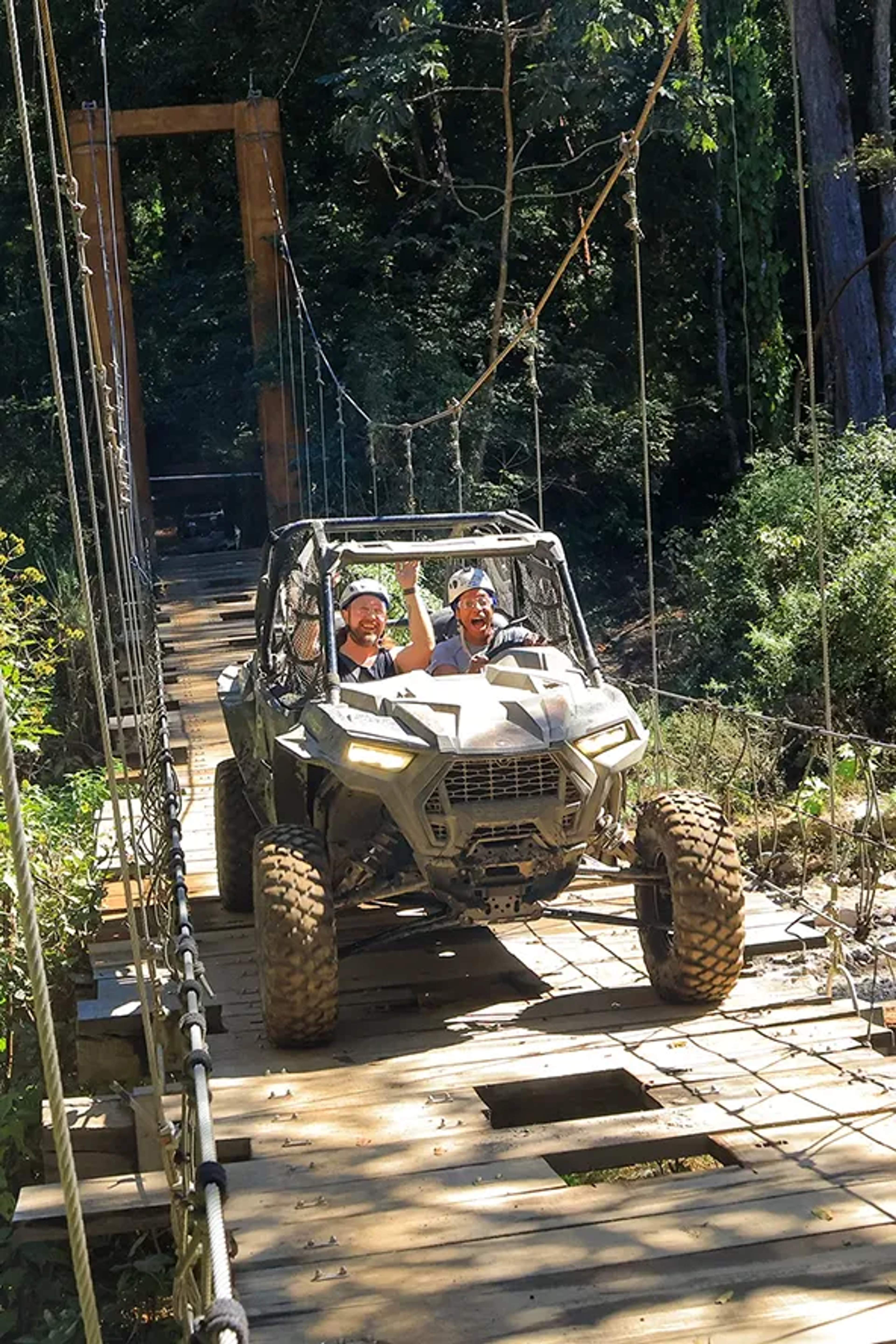 Aventureros cruzan un puente colgante en un vehículo UTV, rodeados de selva tropical en Puerto Vallarta.