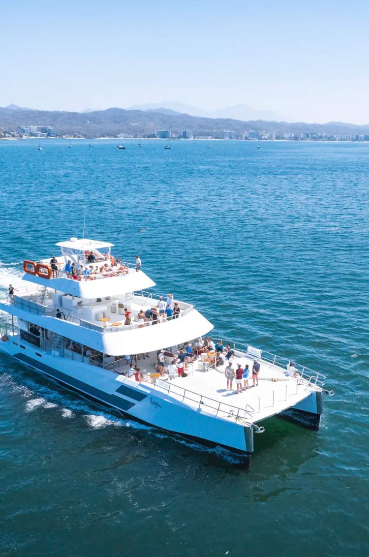 Seventeen private catamaran cruising Banderas Bay with Puerto Vallarta coastline views.