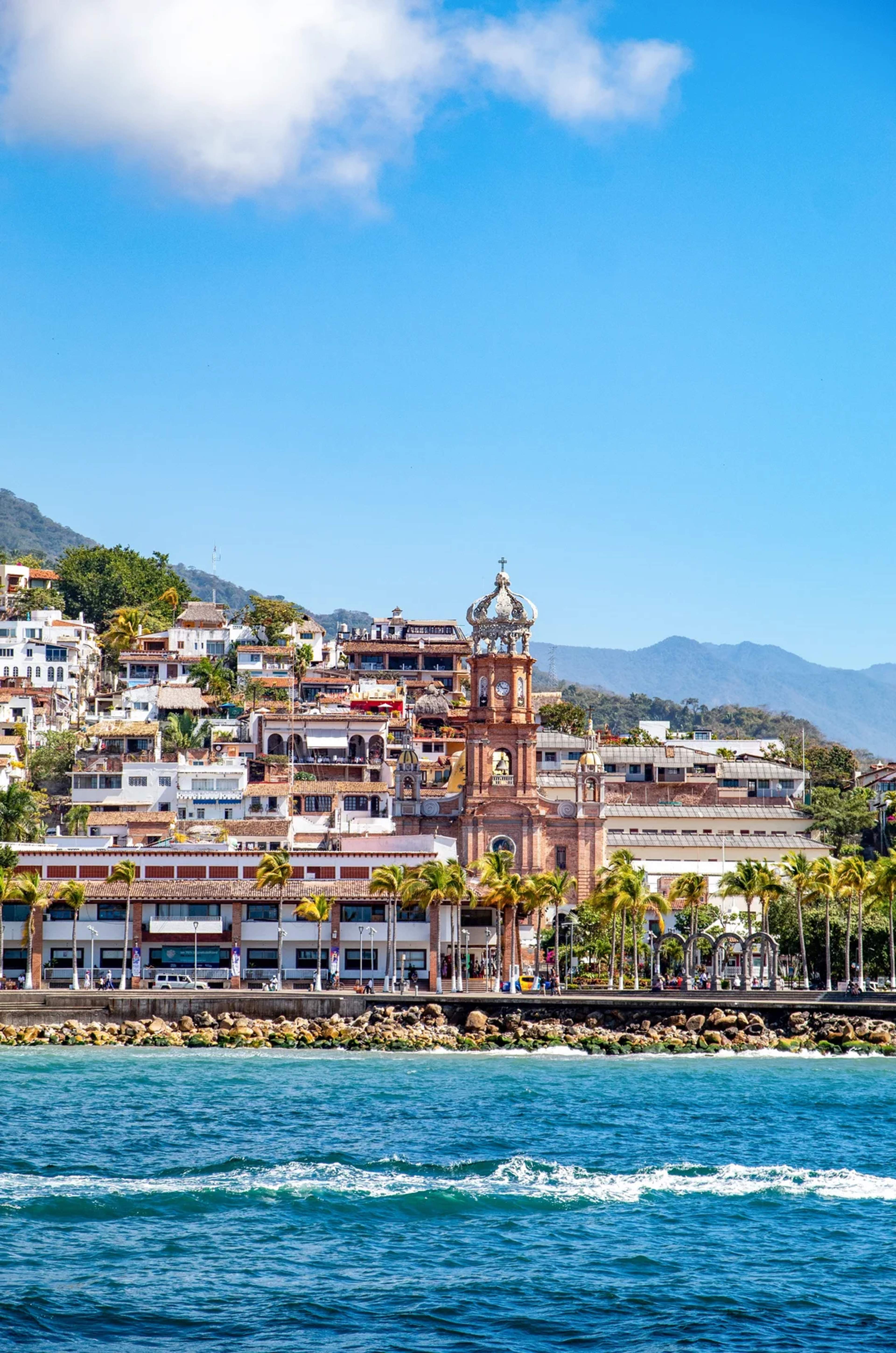 Iglesia icónica de Puerto Vallarta con vista al mar y montañas en un día soleado.