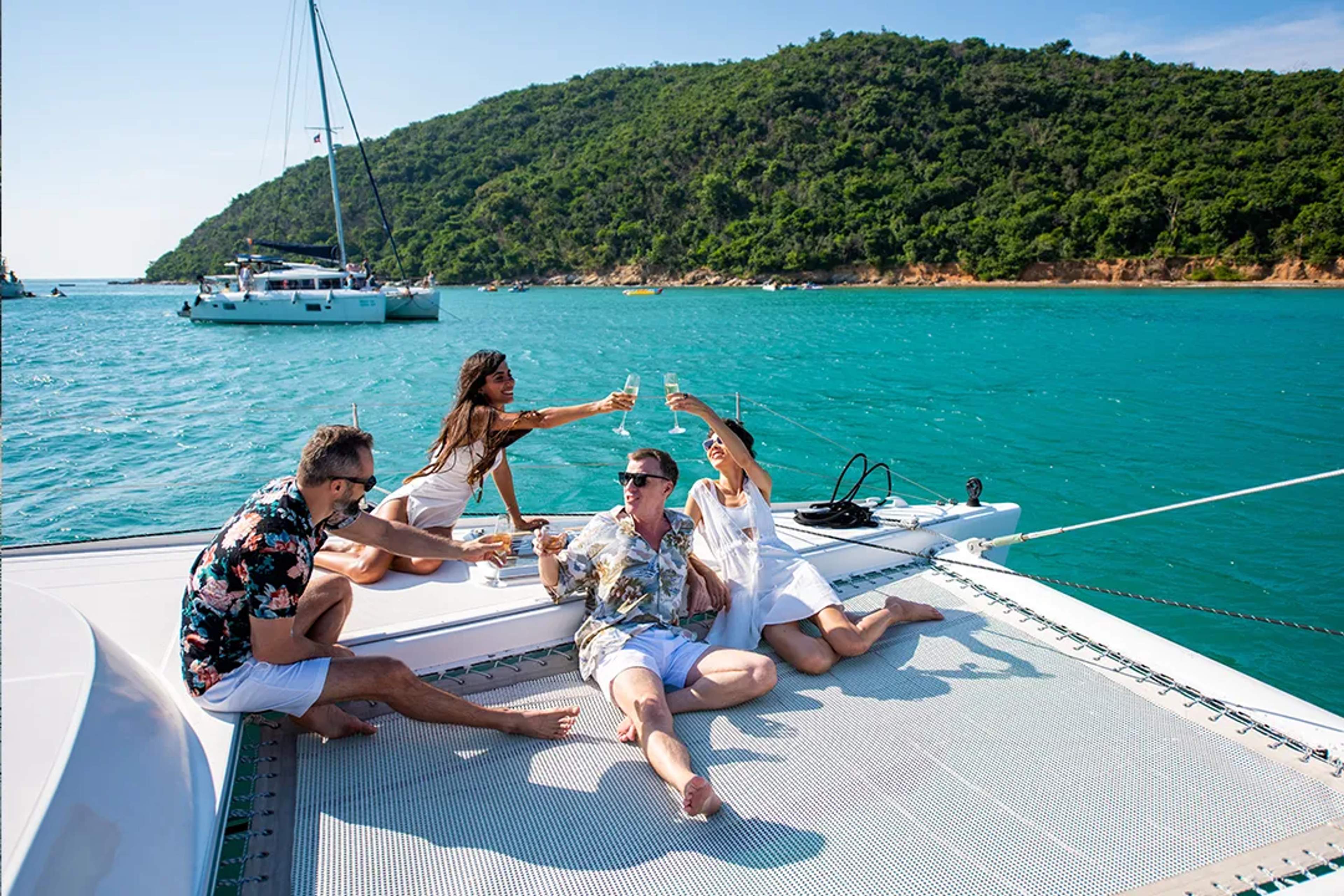 Adults enjoying a catamaran tour in Puerto Vallarta, relaxing with drinks on a tropical bay.