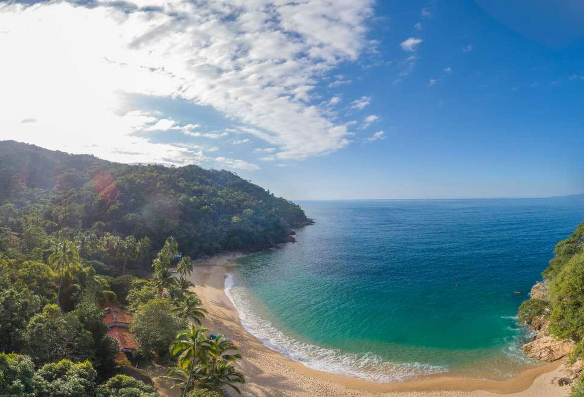 Scenic beach with clear turquoise waters and lush green hills in Puerto Vallarta.