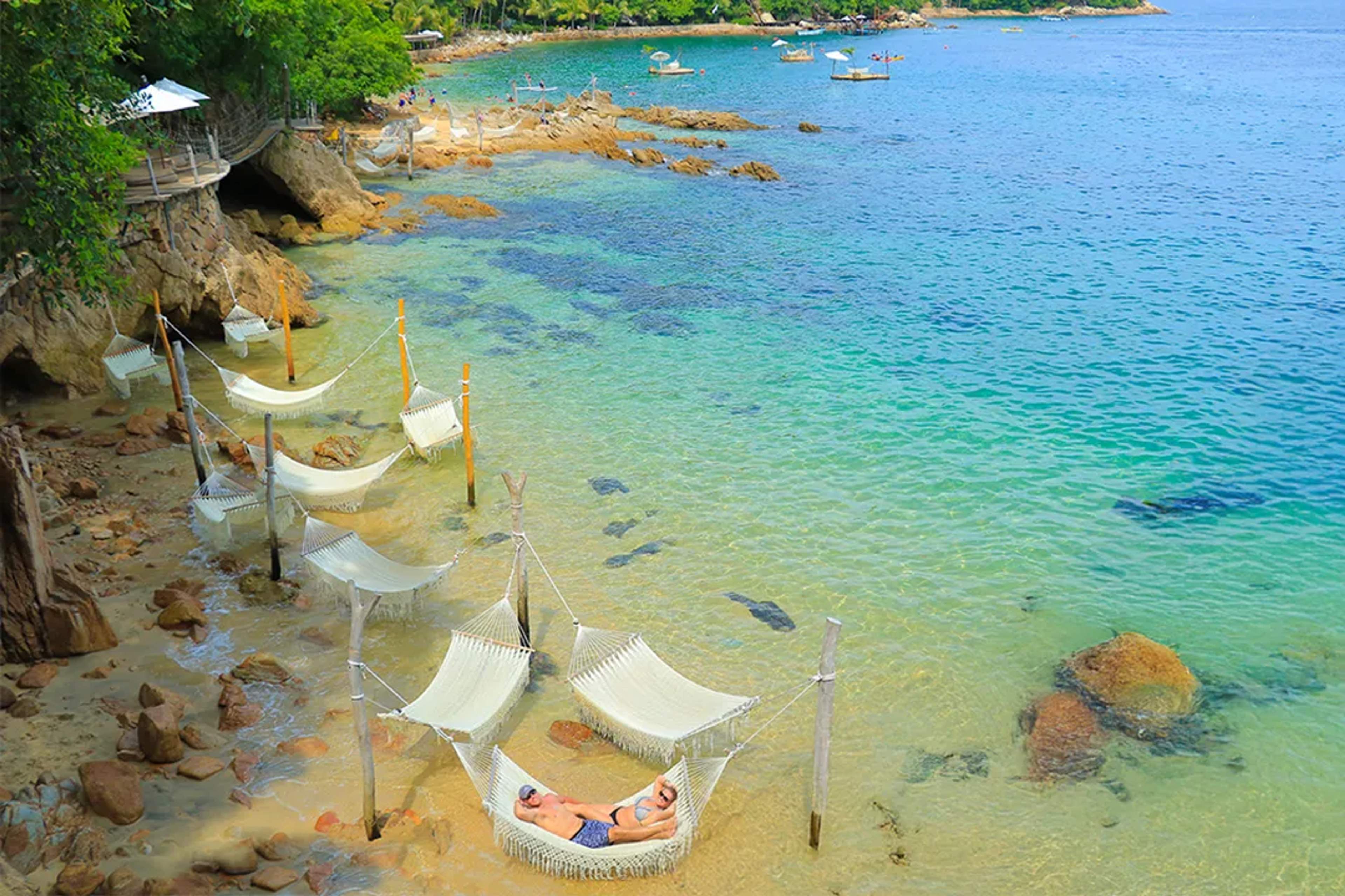 Overwater hammocks at secluded beach near Puerto Vallarta with crystal clear turquoise waters