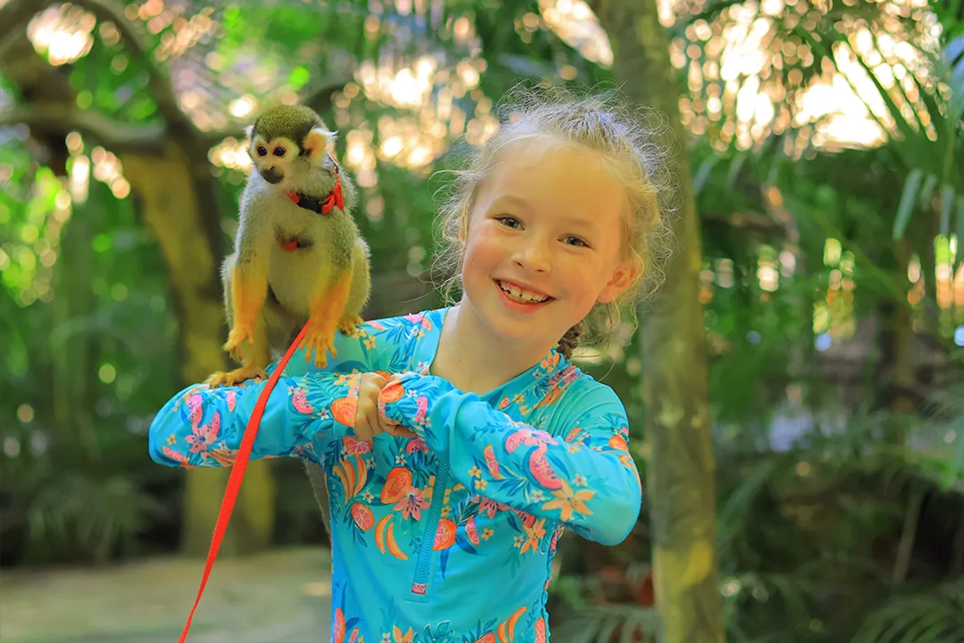 Niña con un mono ardilla durante un encuentro con fauna en Vallarta Adventures, Puerto Vallarta