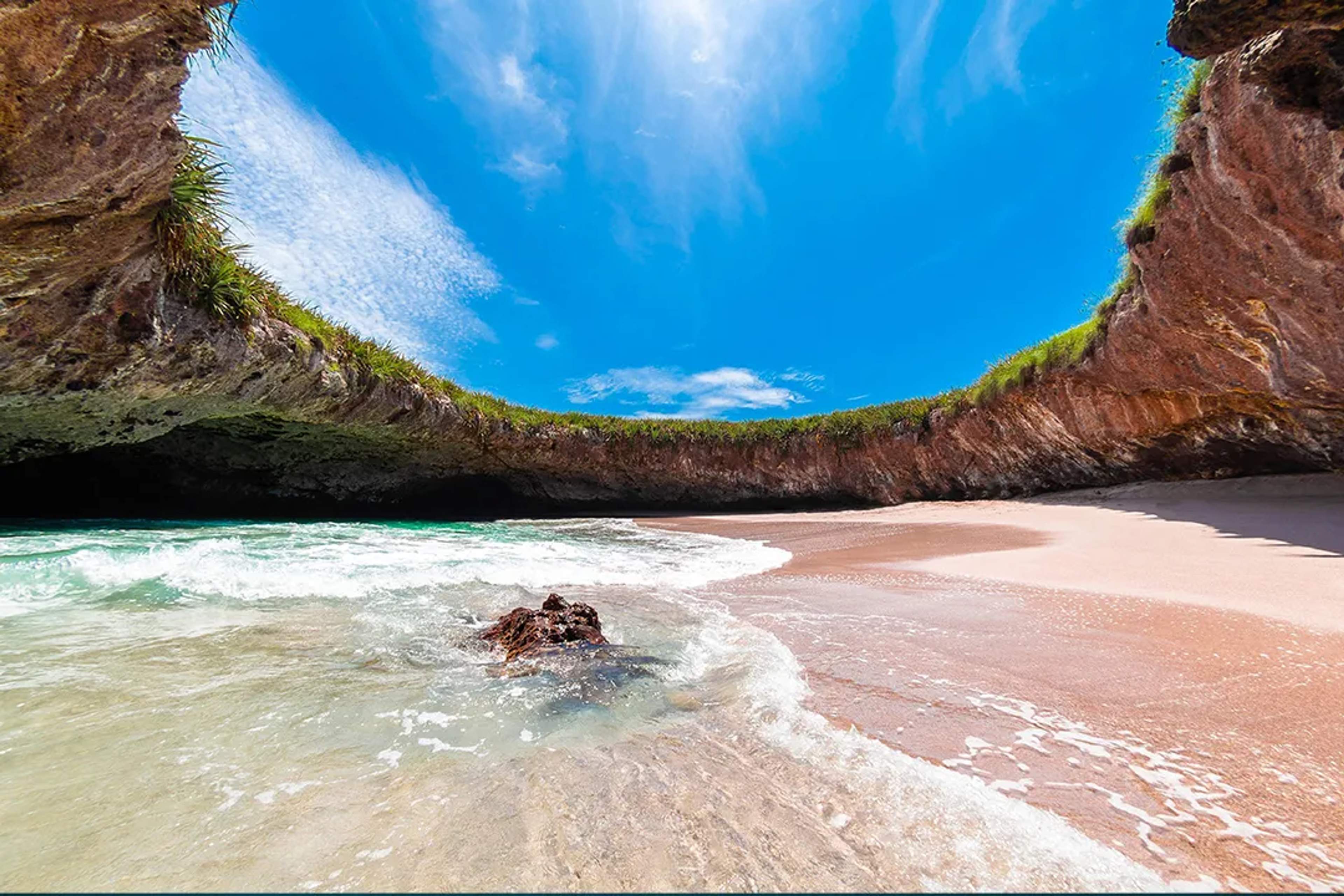 Hidden Beach reveals turquoise waves and golden sand under a bright blue sky.