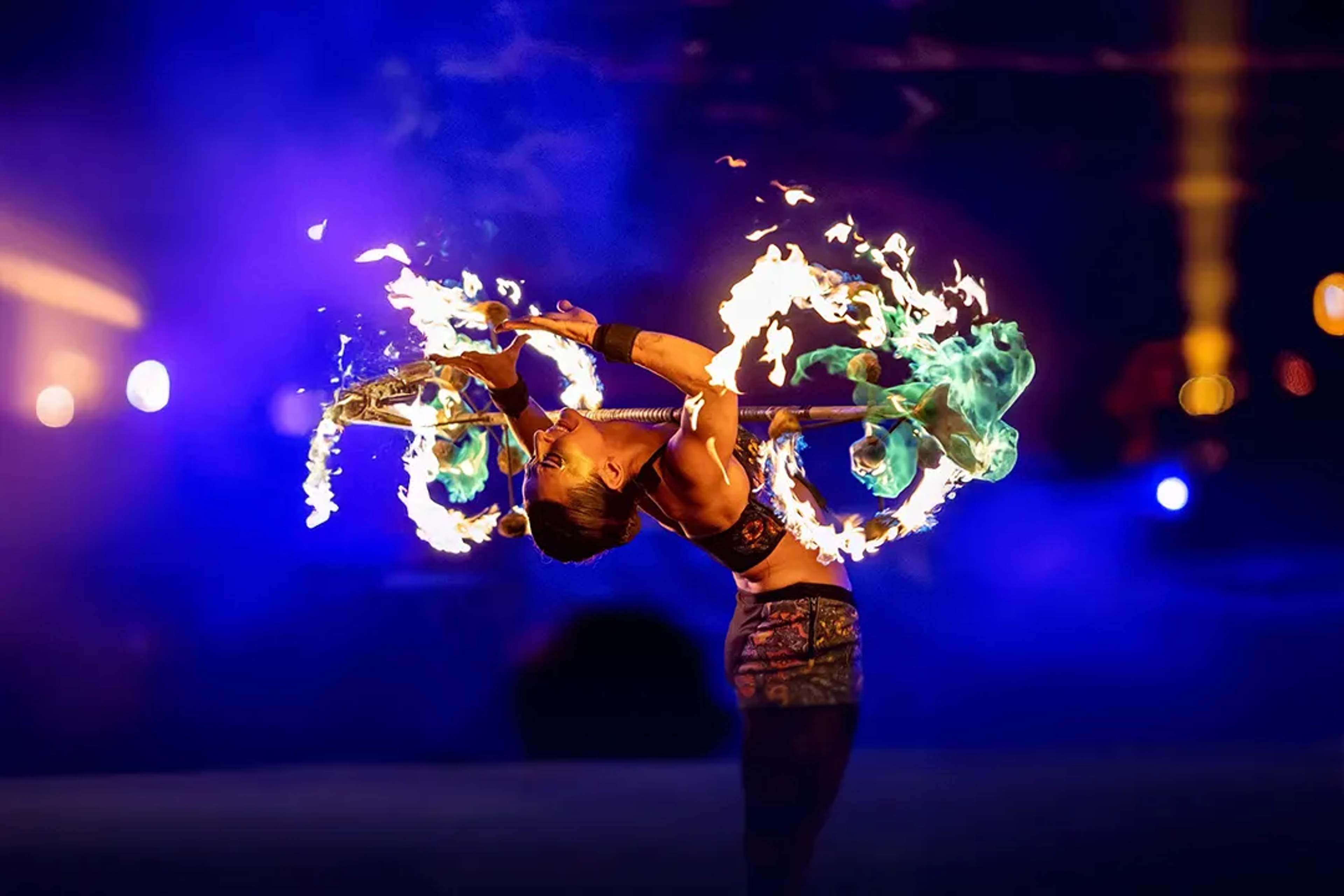 Artista de fuego doblándose bajo aro en llamas en ALMA, Ritmos de la Noche en Puerto Vallarta