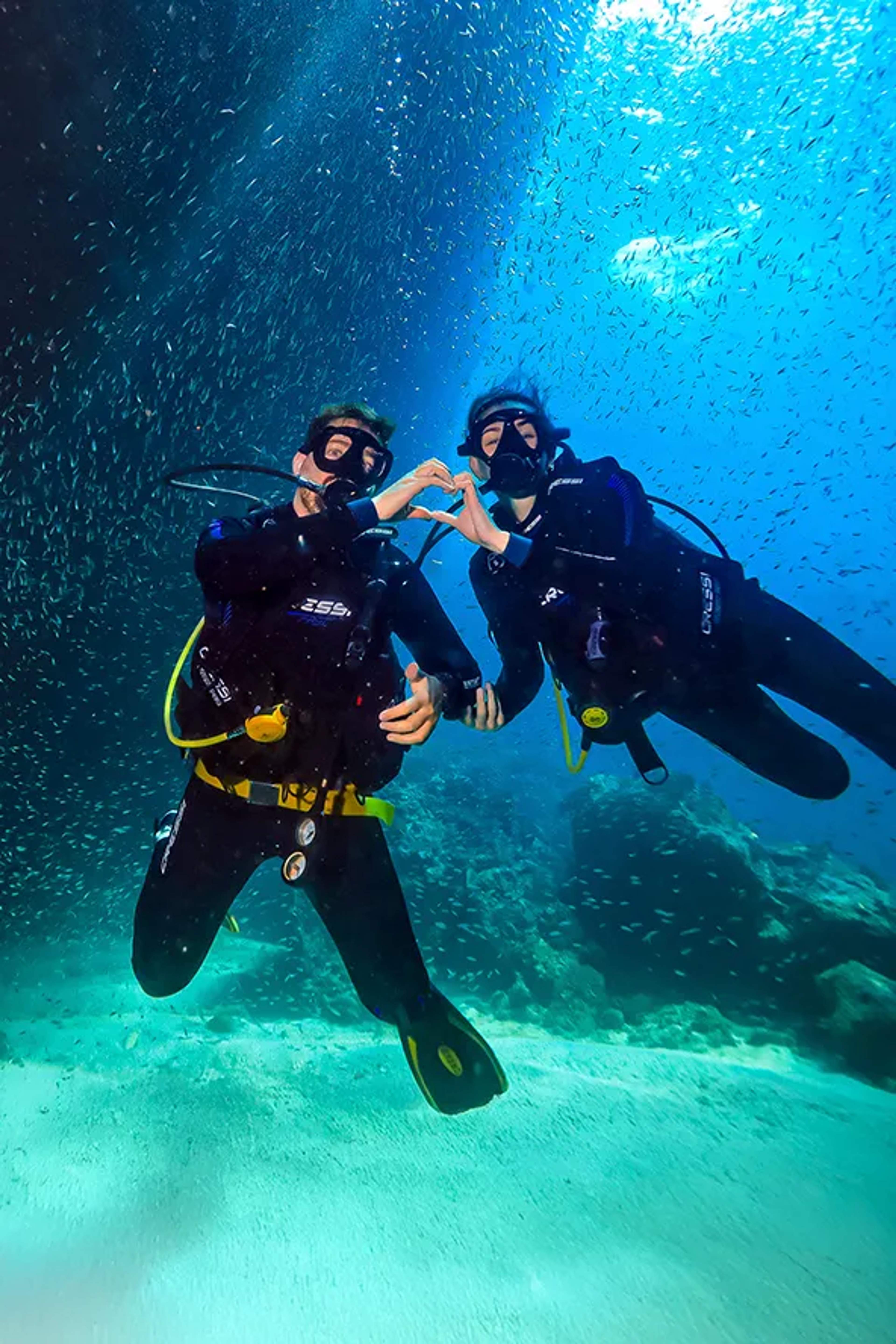 Couple scuba diving in Puerto Vallarta, surrounded by tropical fish on an unforgettable underwater tour.