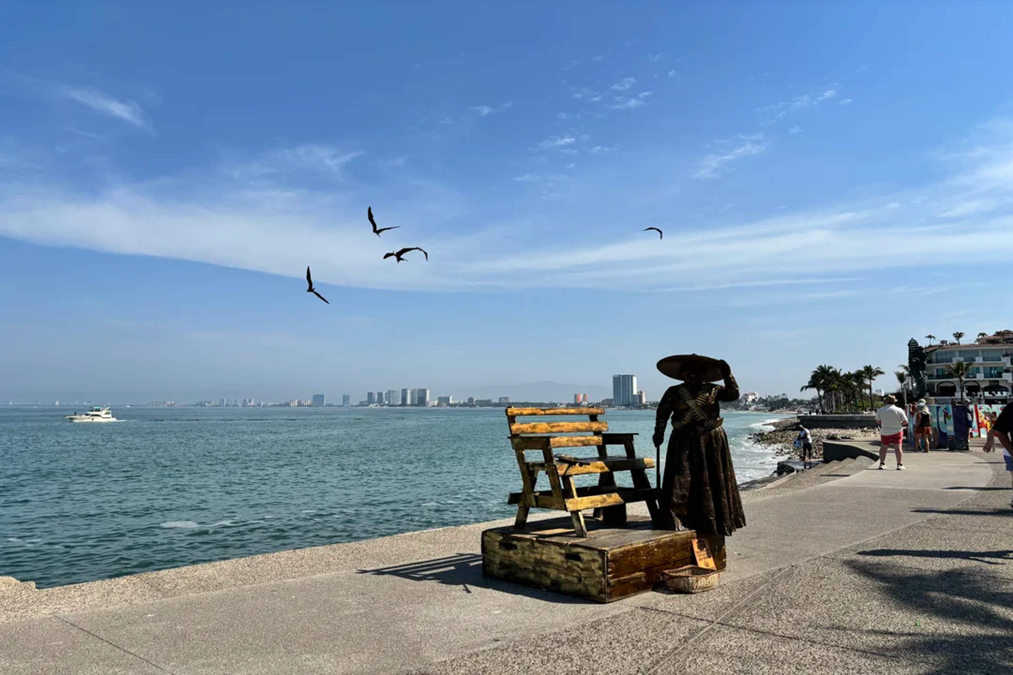 Oceanfront statue and cityscape along Puerto Vallarta’s scenic Malecón under a sunny sky.