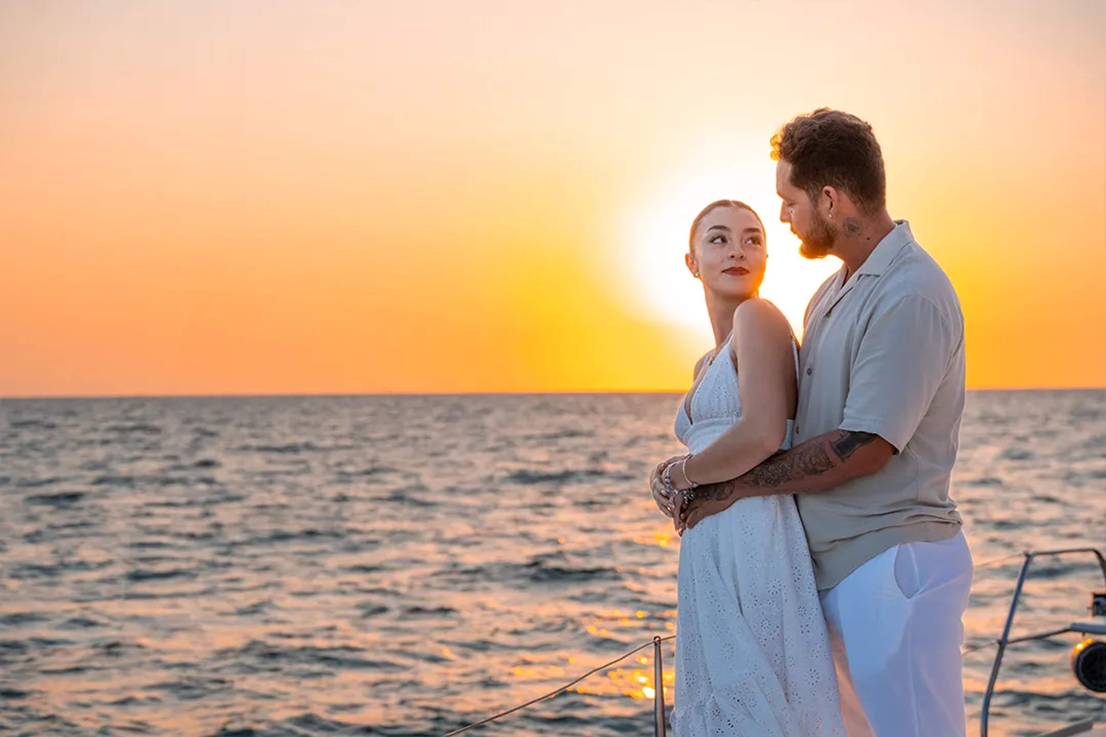 Romantic couple embracing at sunset during a Sunset Sailing experience in Puerto Vallarta with golden ocean views