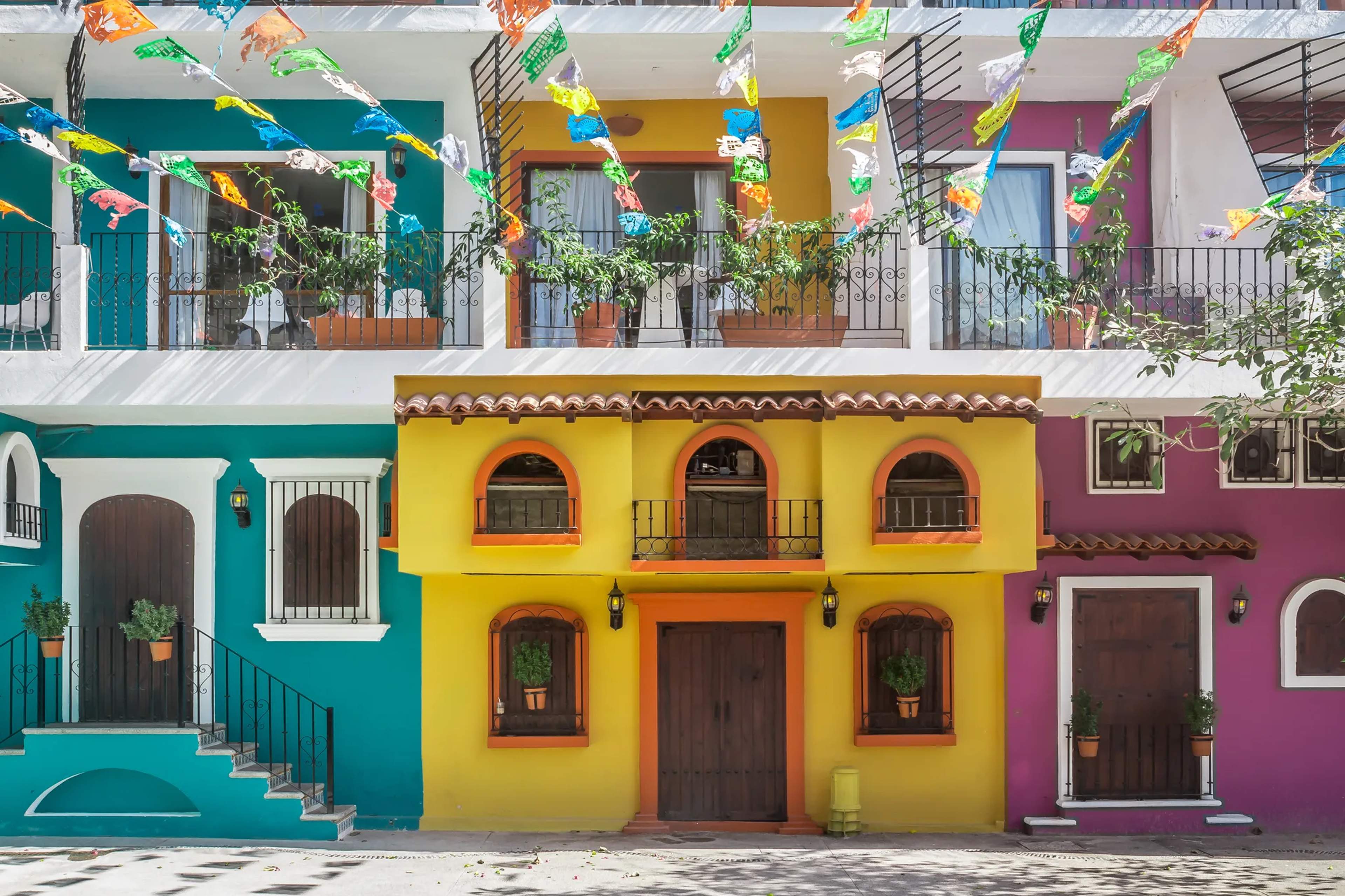Coloridos edificios de estilo colonial en el centro histórico de Puerto Vallarta decorados con banderines de papel y macetas