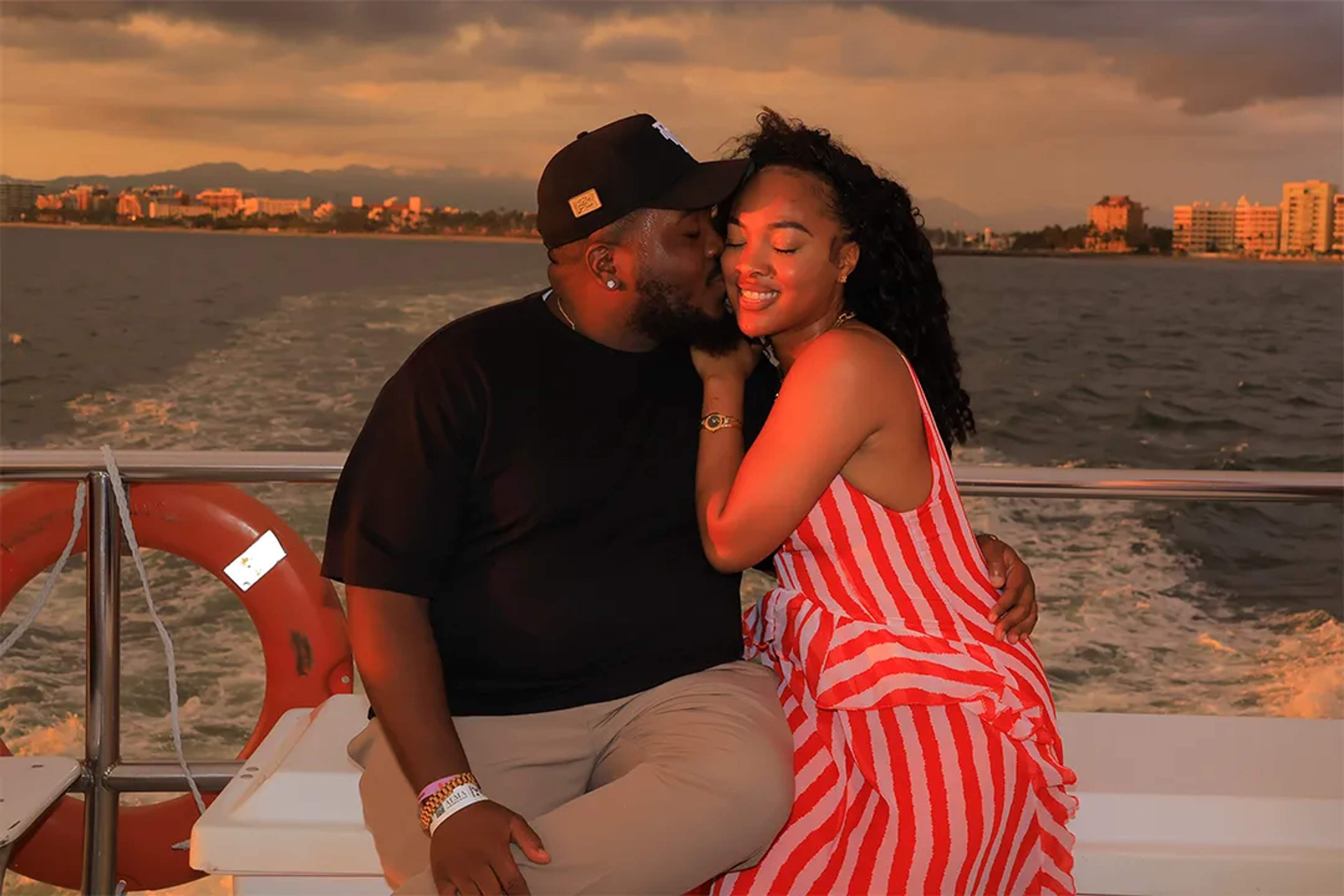 Romantic sunset moment on a boat, couple embracing with city skyline in the background.
