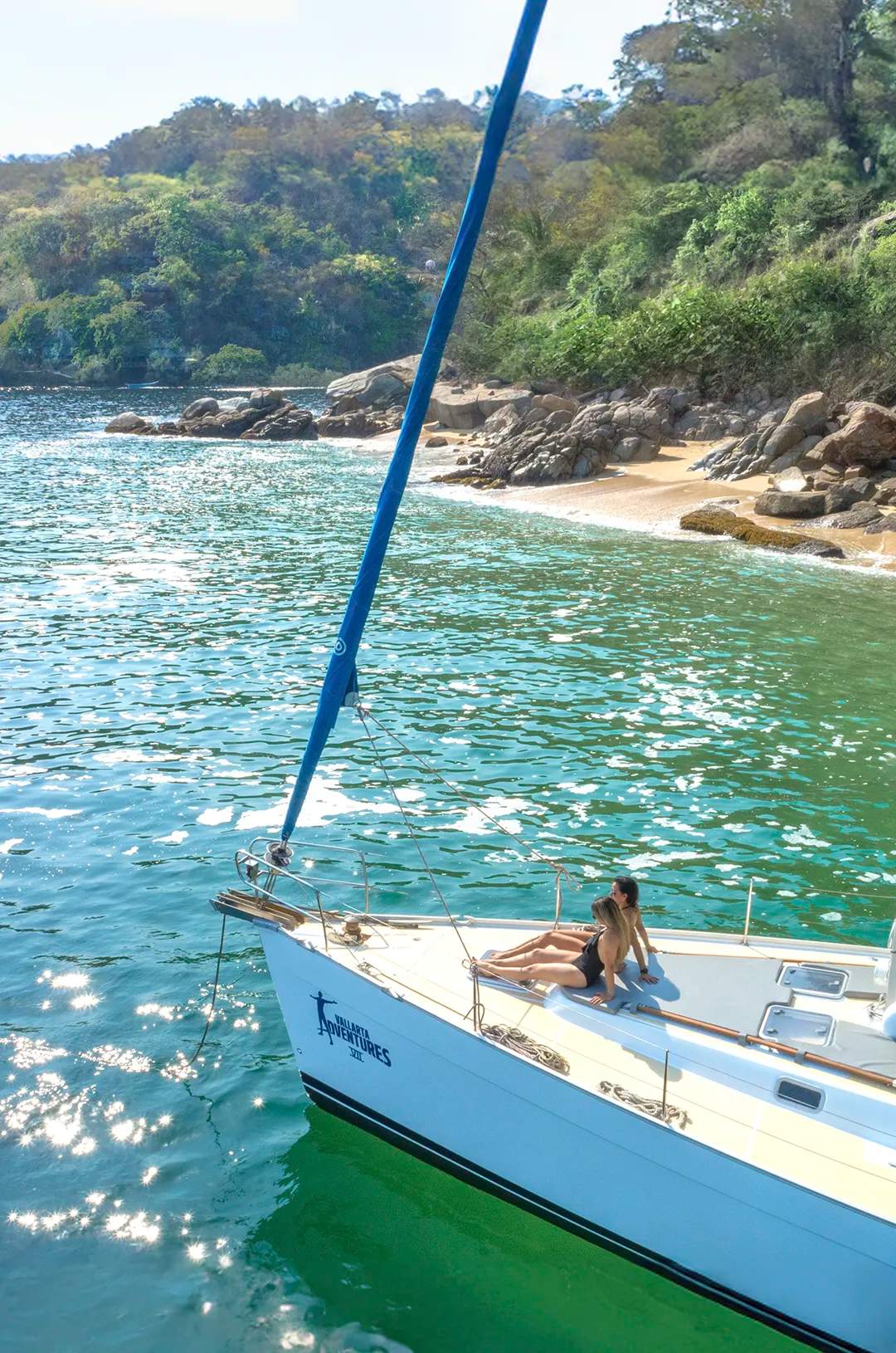 Un velero anclado en la costa sur de Puerto Vallarta con vegetación exuberante y aguas tranquilas.