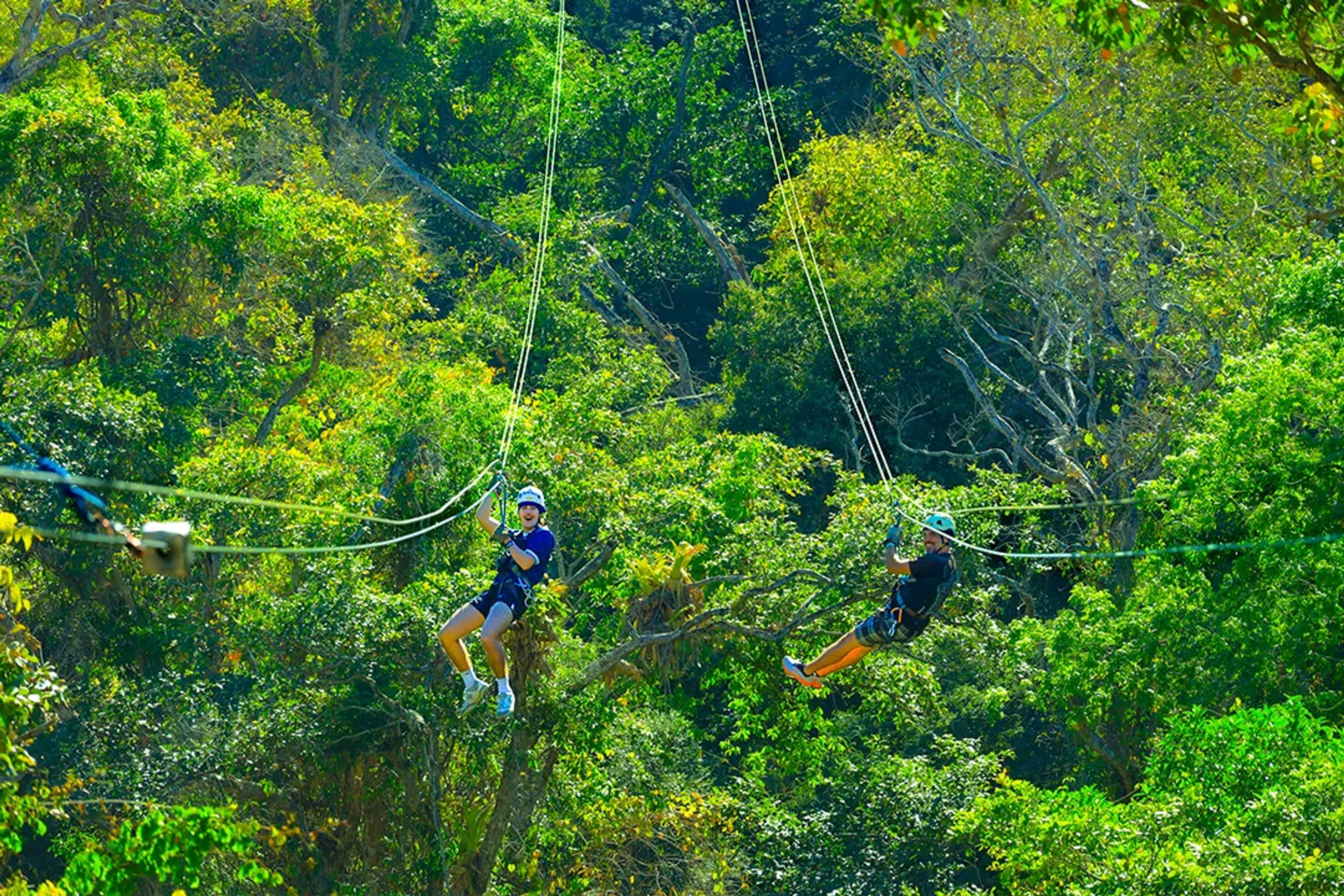 Guests zip-lining through Puerto Vallarta jungle on Outdoor Adventure tour, soaring above Sierra Madre canopy.