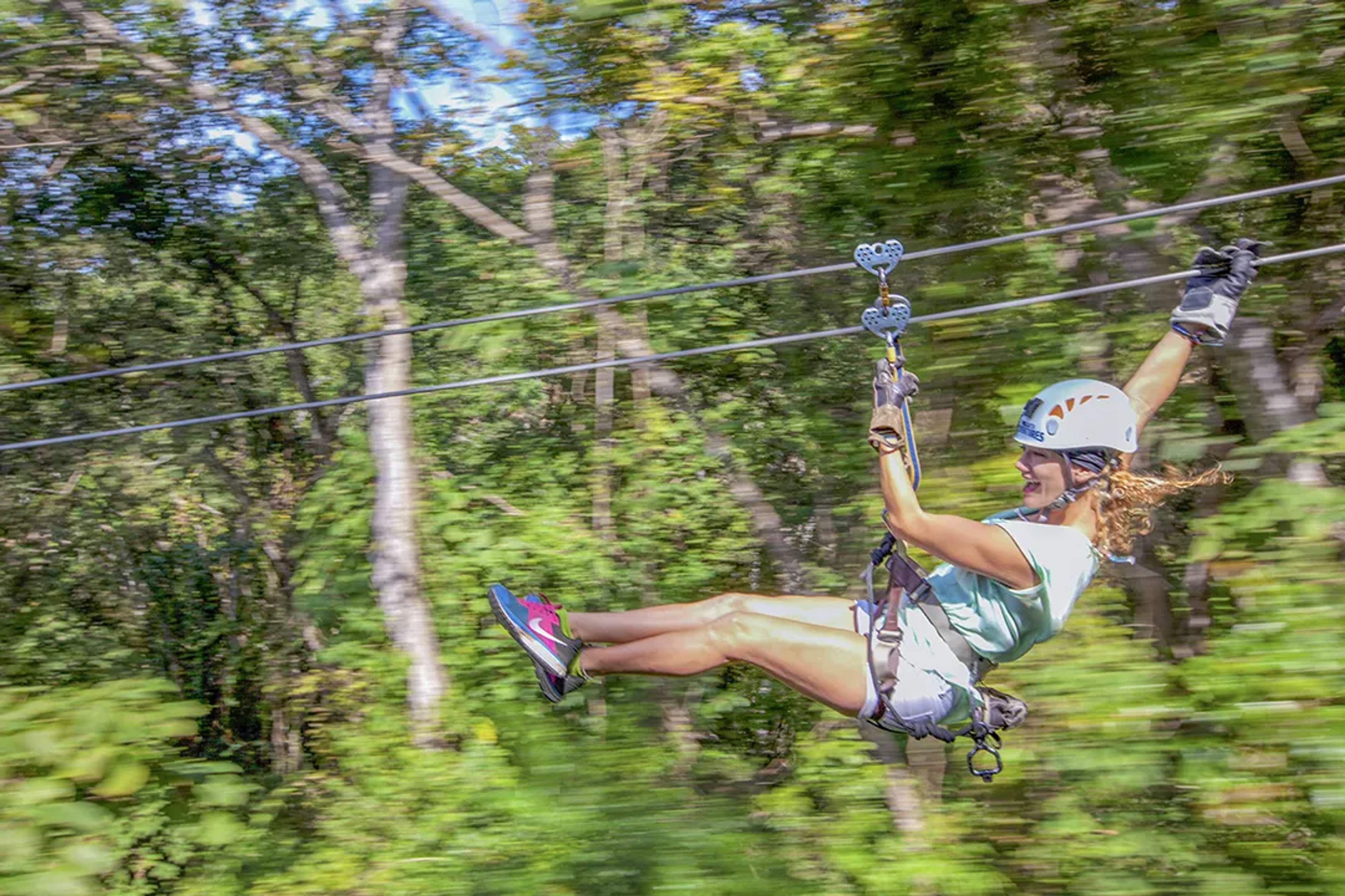 Woman ziplining through the lush jungle canopy on the Extreme Adventure tour in Puerto Vallarta.