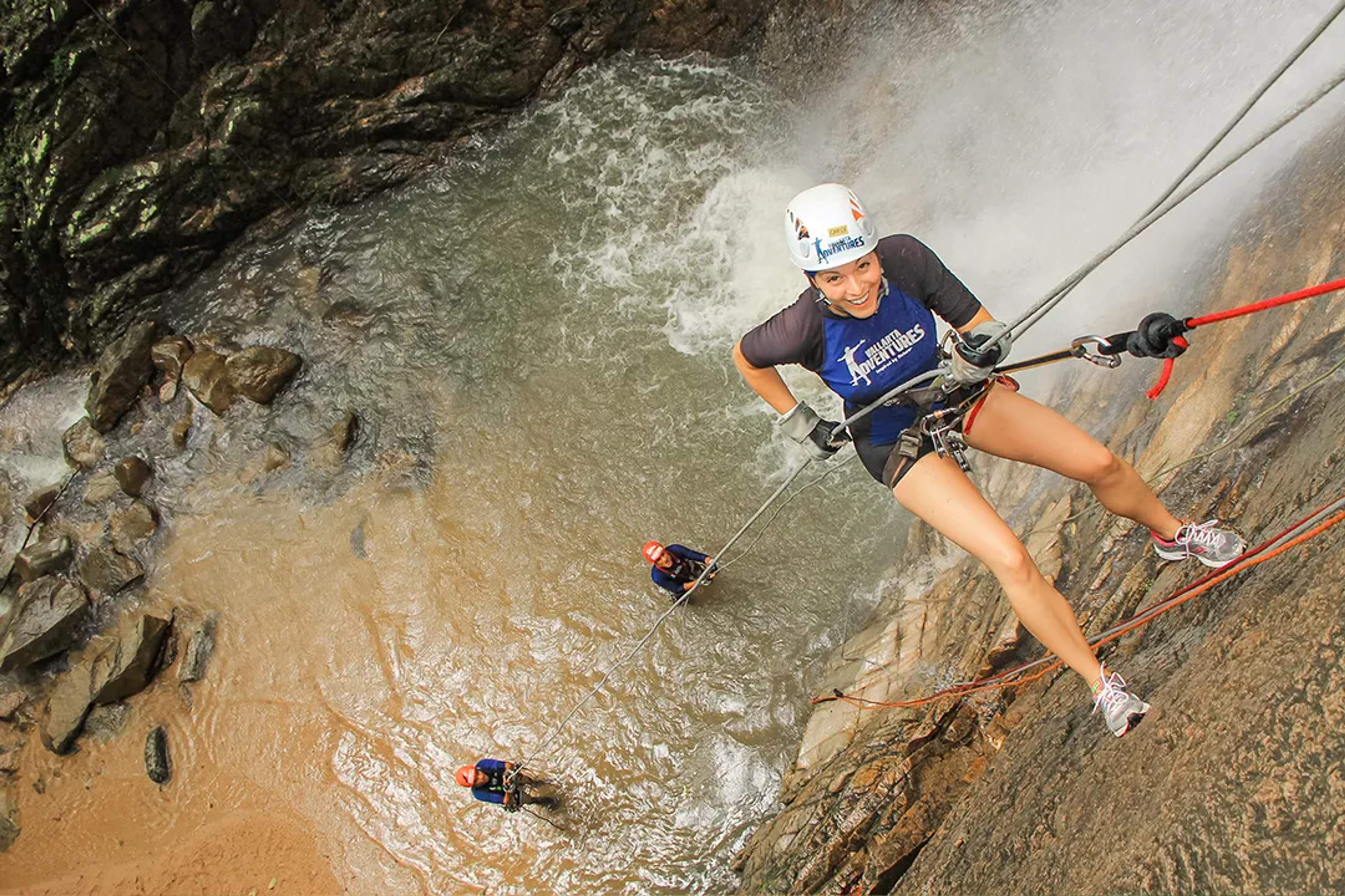 Woman rappels down a waterfall on Vallarta Adventures Outdoor Adventure tour in the jungle