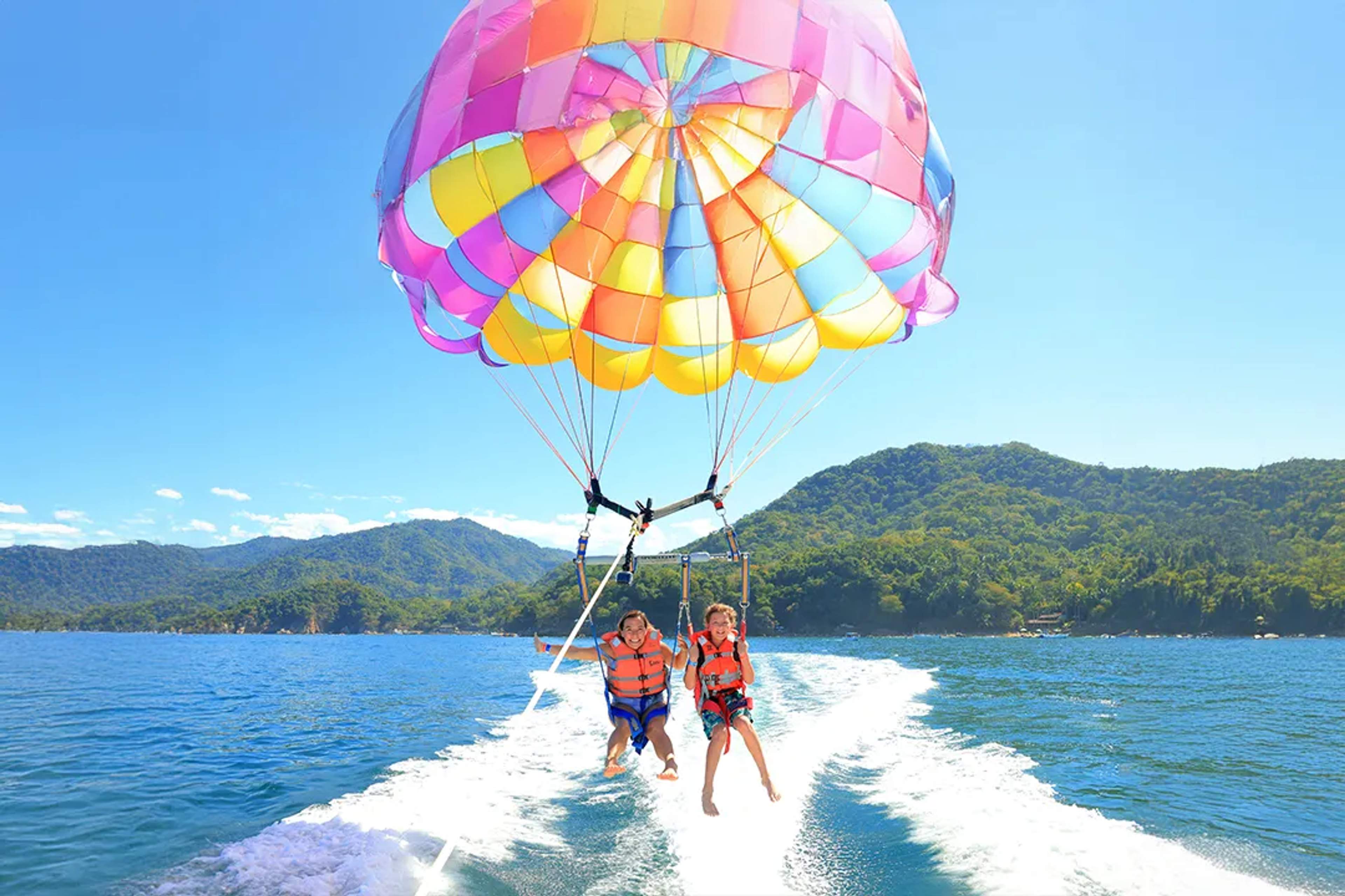 Kids parasailing in Puerto Vallarta over Banderas Bay with jungle mountains on a fun adventure tour