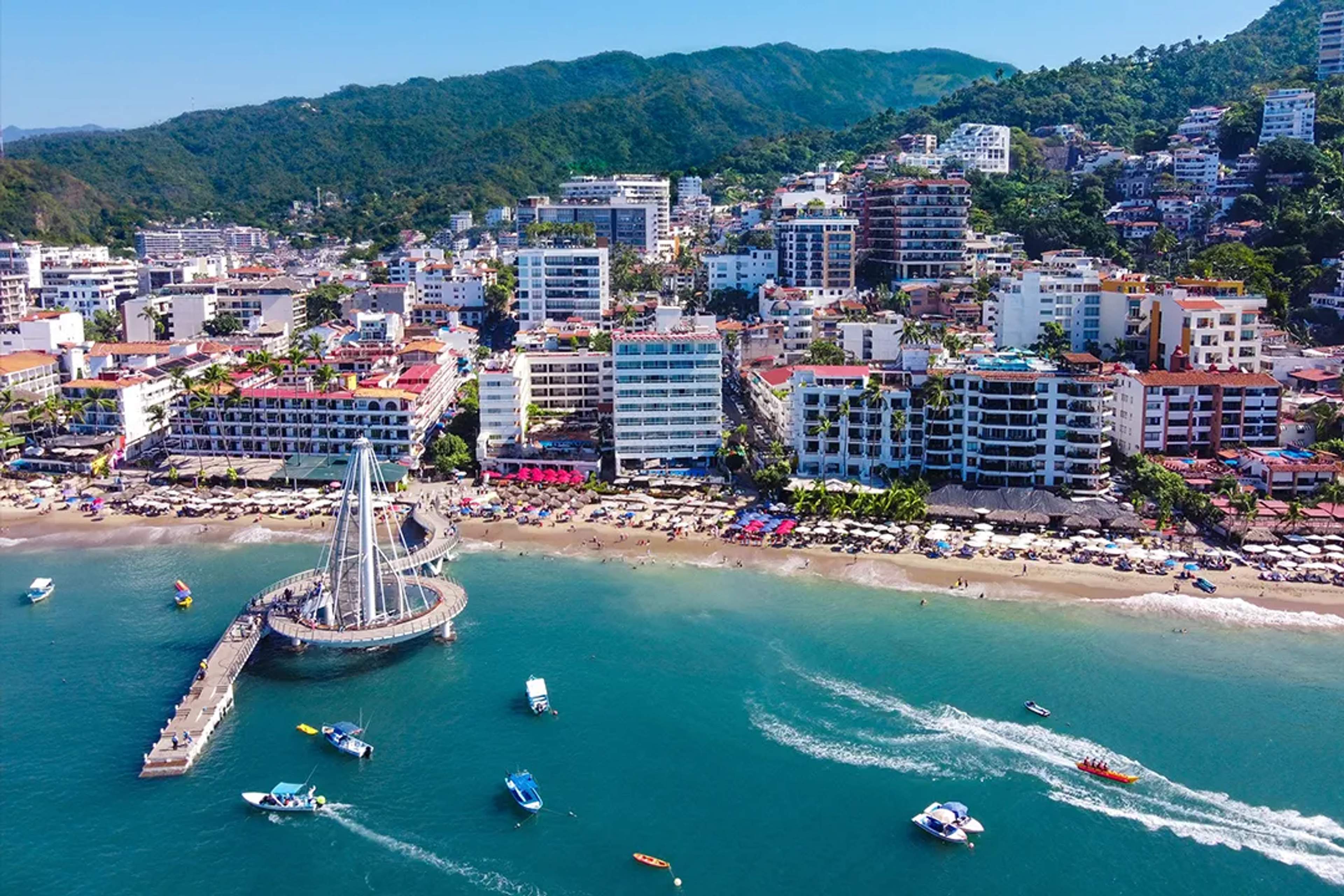 Aerial view of Los Muertos Pier and beachfront in Puerto Vallarta with boats, waves and city skyline