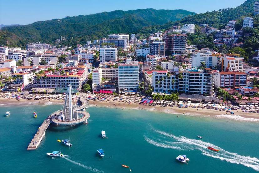 Aerial view of Los Muertos Pier and beachfront in Puerto Vallarta with boats, waves and city skyline
