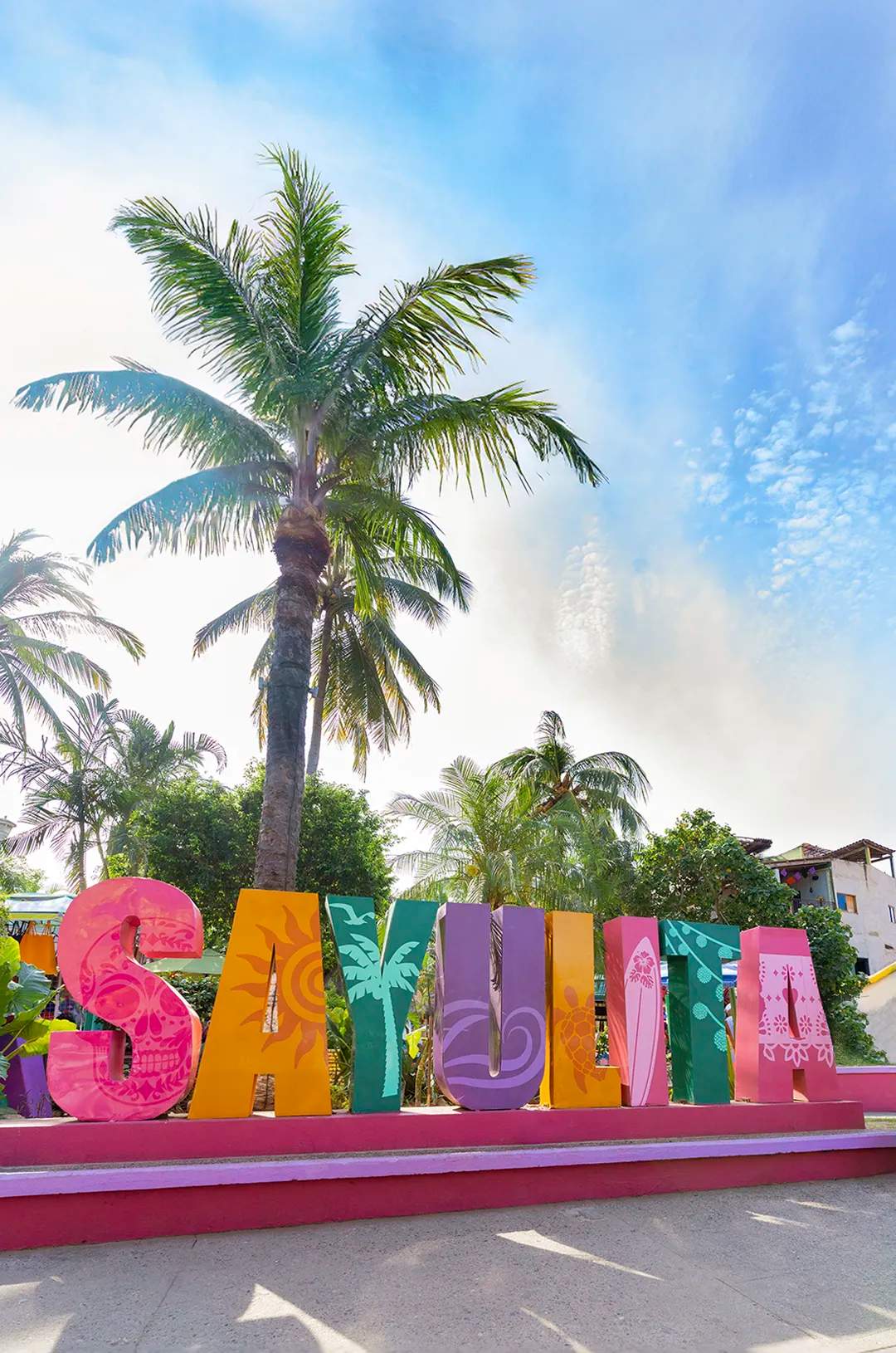 Colorful 'SAYULITA' sign with tropical palms in the background.